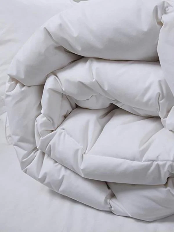 Close-up of white bedding or duvet folded or rolled up.