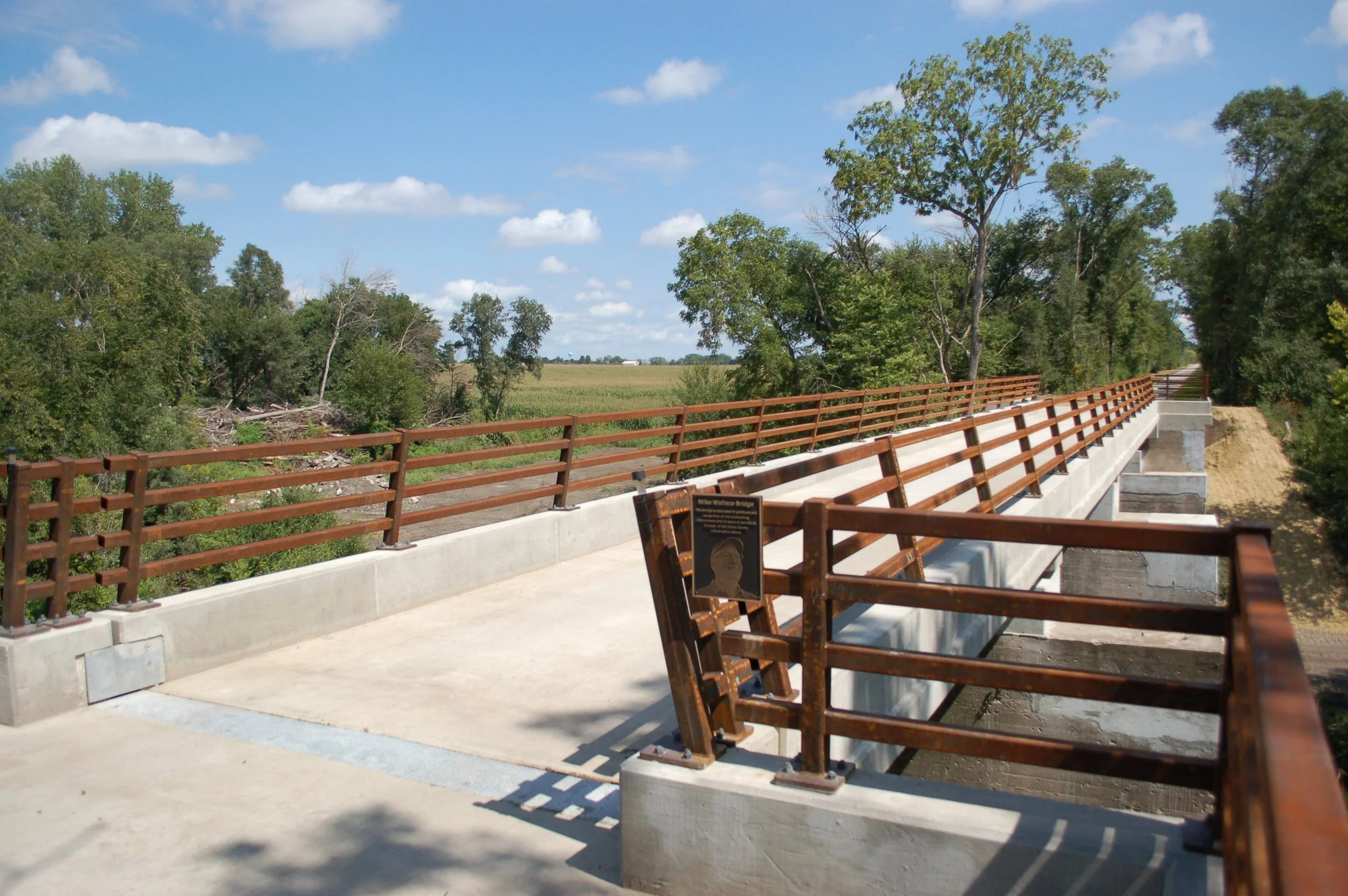 View of the Mike Wallace Bridge post construction over a rural area with trees and open land, with blue sky and clouds.
