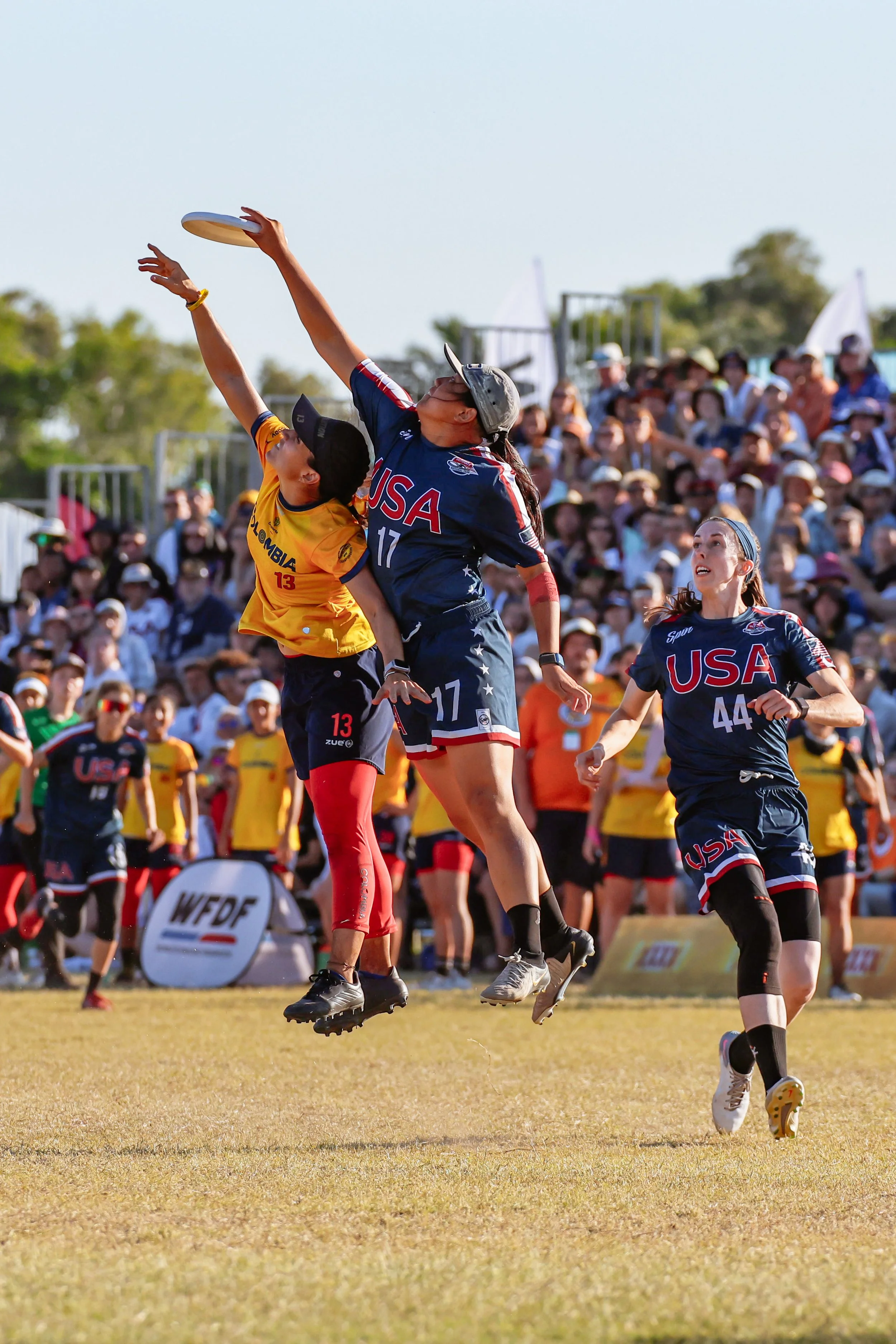 Women playing in the Finals of the World Ultimate (Frisbee) Championships in 2024, with one player jumping to catch the frisbee as another attempts to block.