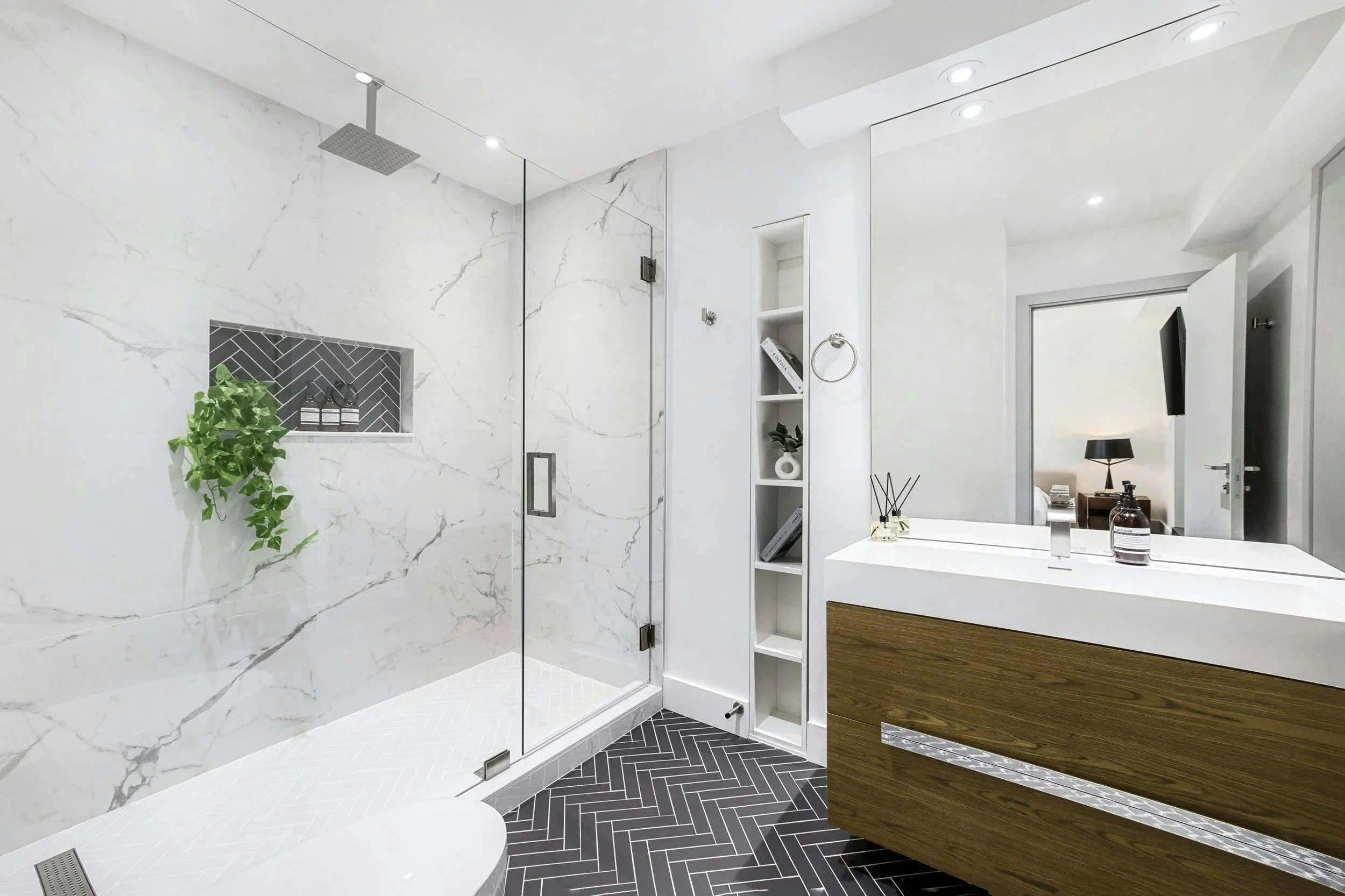 Marble-look tile shower with a recessed niche, patterned floor and wood vanity