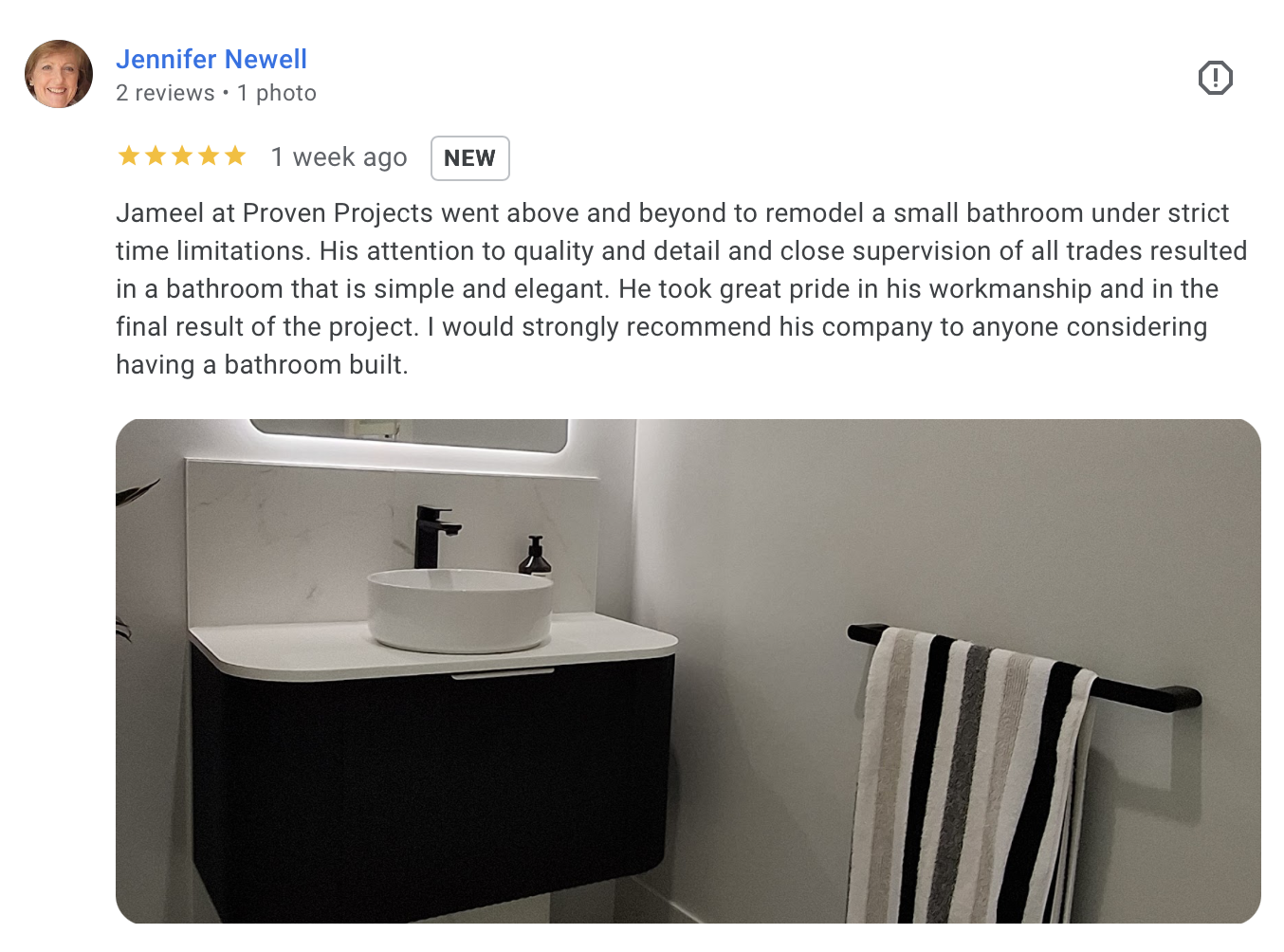 Modern bathroom with a black cabinetry vanity, white vessel sink, black faucet, soap dispenser, and a striped towel on a black towel rack.
