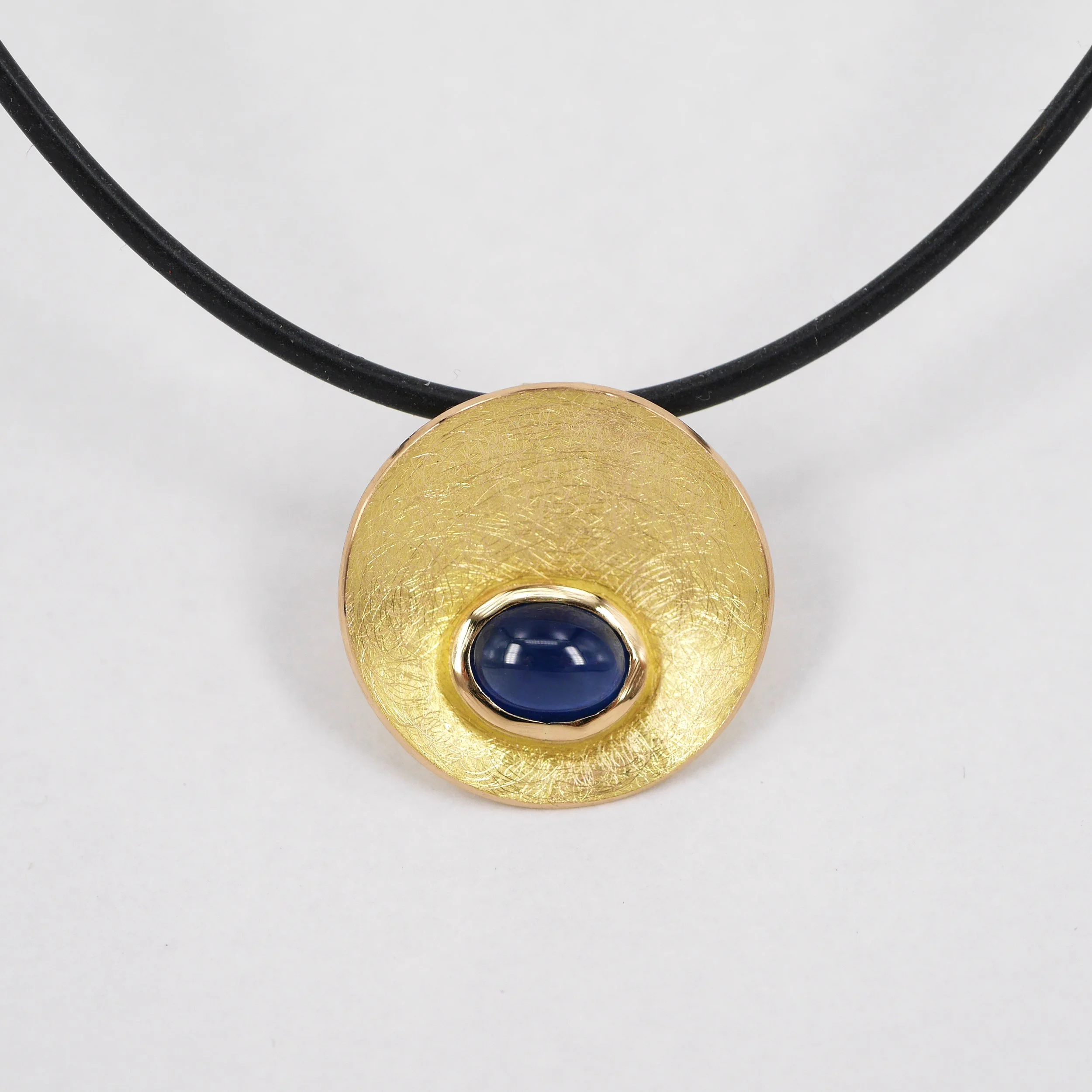 "Konkav" 750er Gelbgold mit Saphir Cabochon auf Kautschukreif