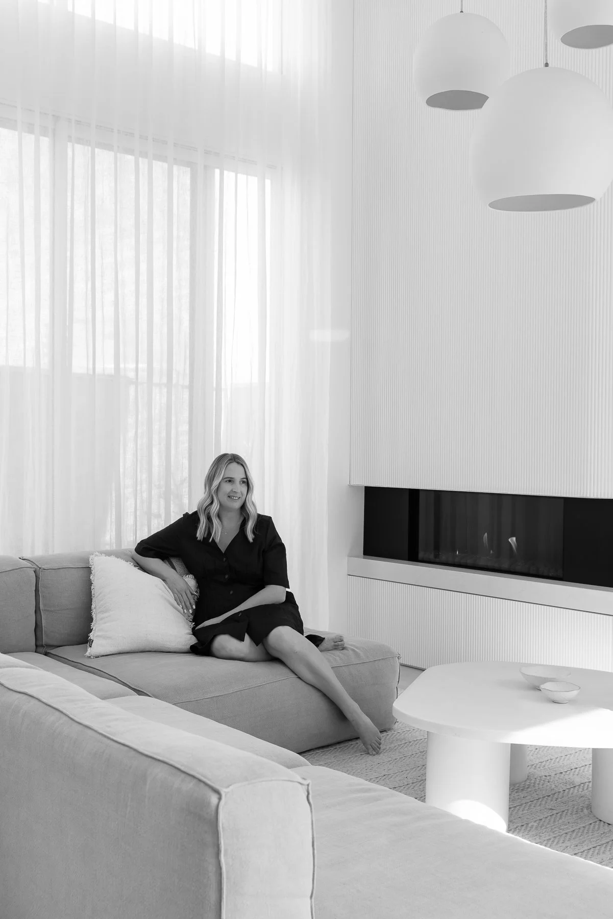 Hayley seated on a sofa in a bright living room with a fireplace