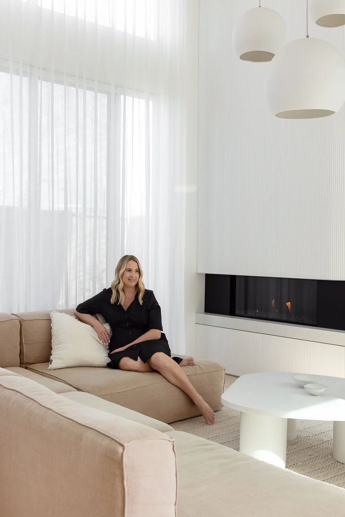 Hayley seated on a beige sofa in a bright, minimal living room