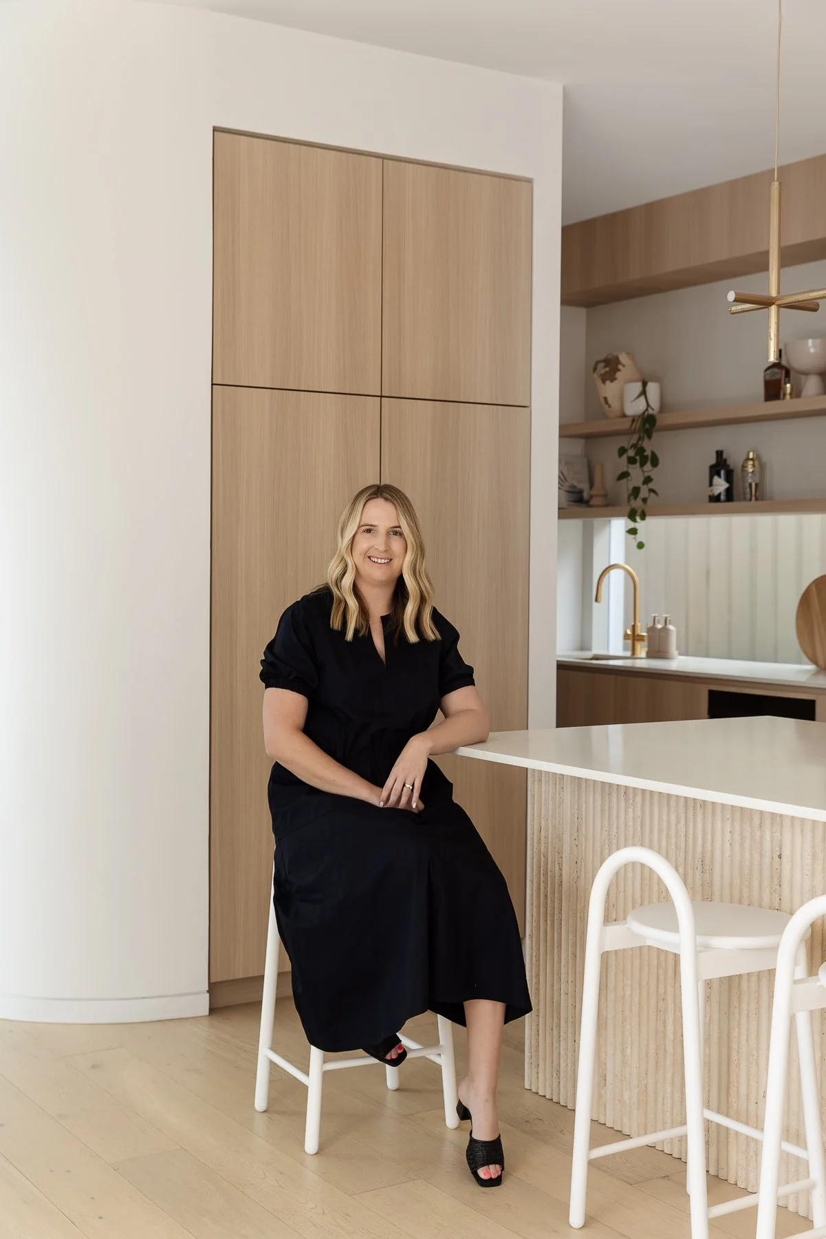 Hayley seated at a kitchen bench in a modern, light-filled kitchen