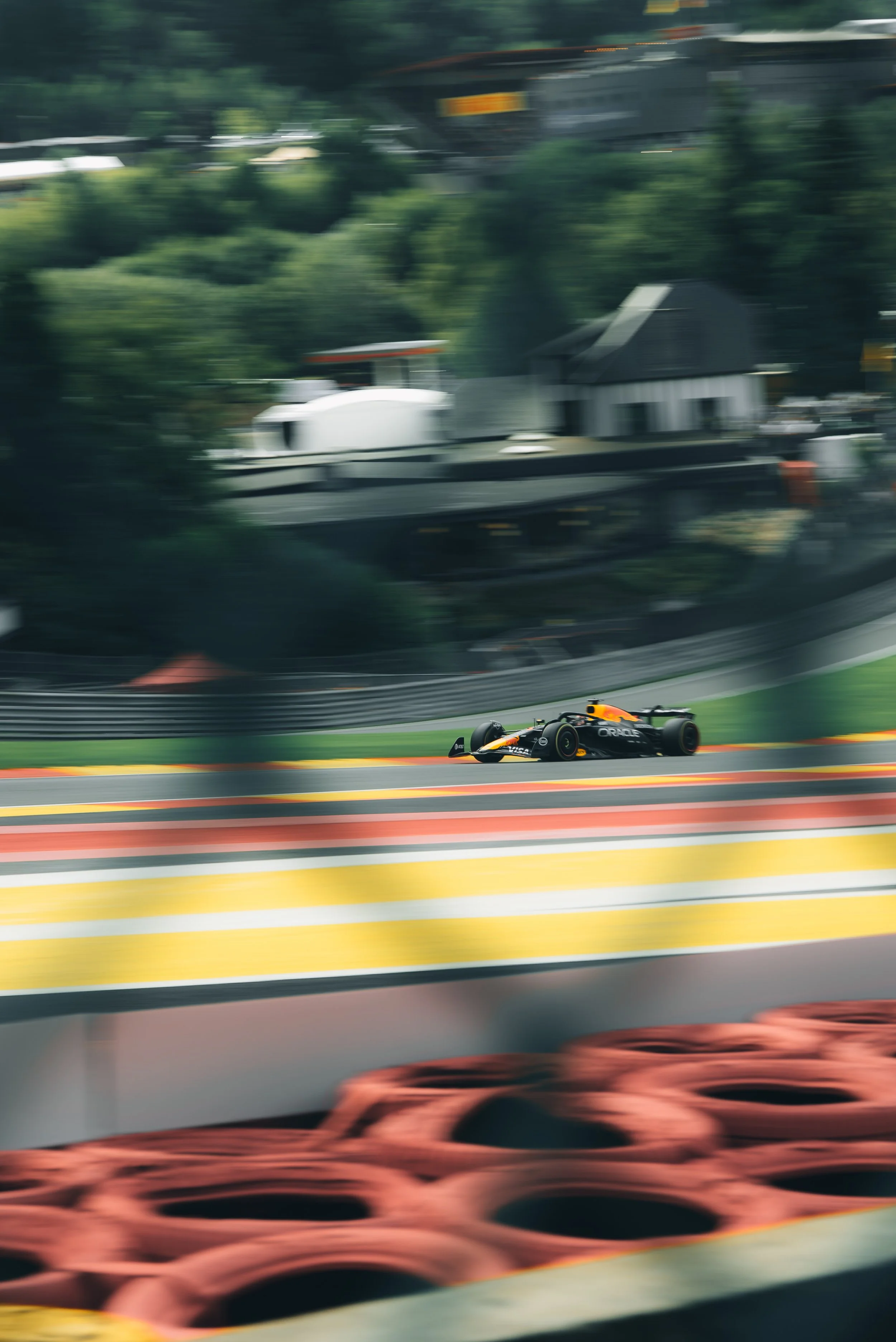 A race car on a track with colorful stripes, blurred background indicating high speed, with tires stacked in the foreground.