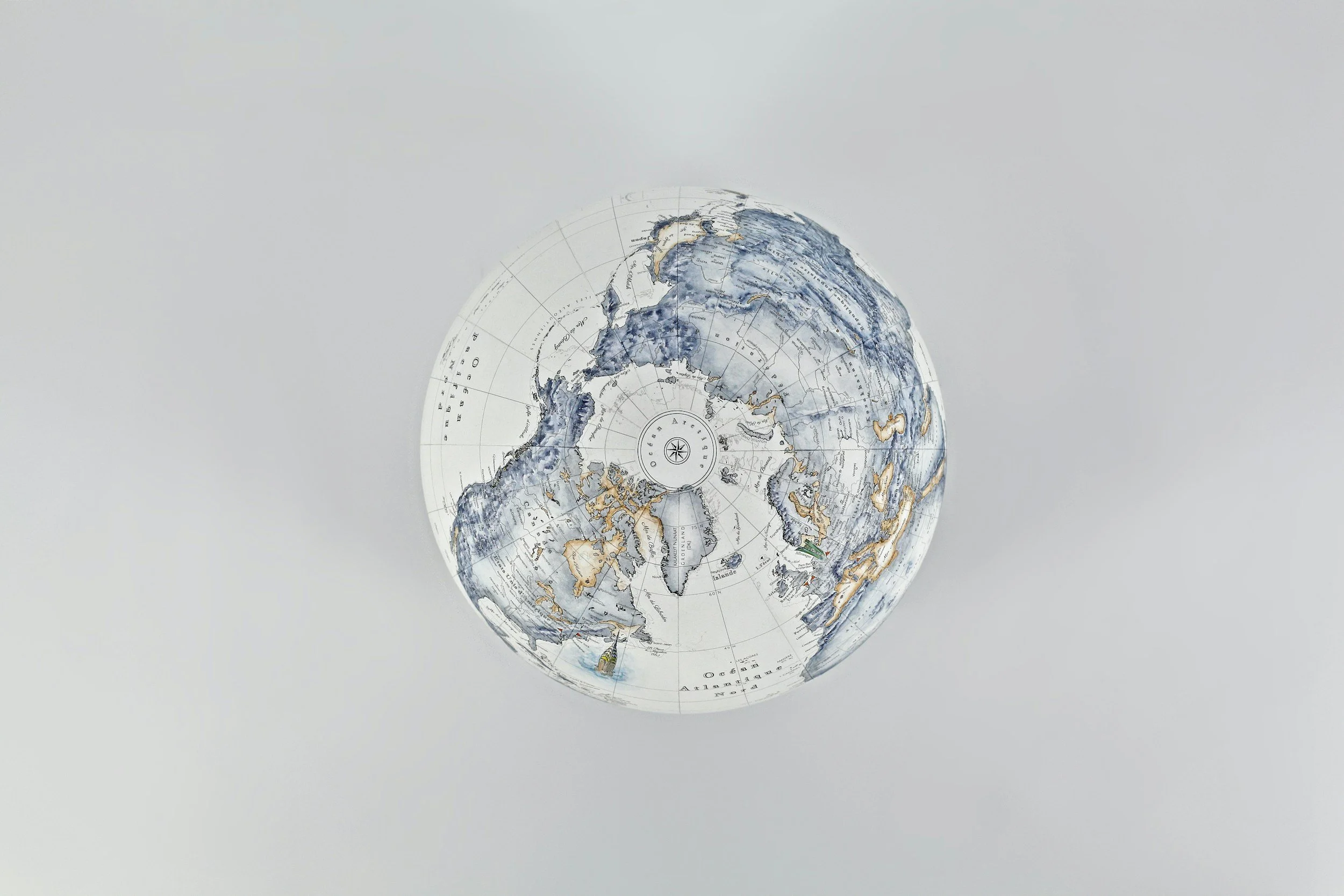 A physical globe showing the northern hemisphere with oceans, countries, and continents on a plain, light-colored background.