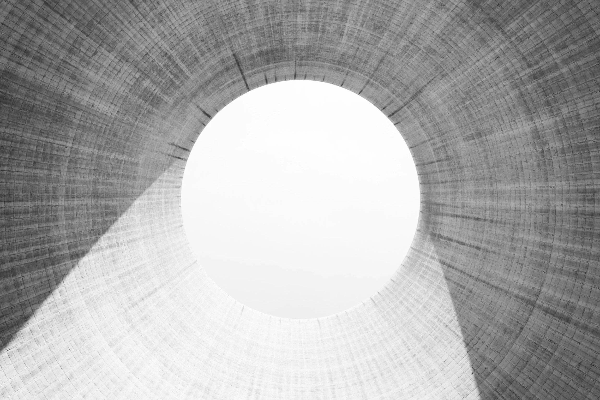 Looking up inside a large concrete cooling tower, showing its circular structure with an opening at the top