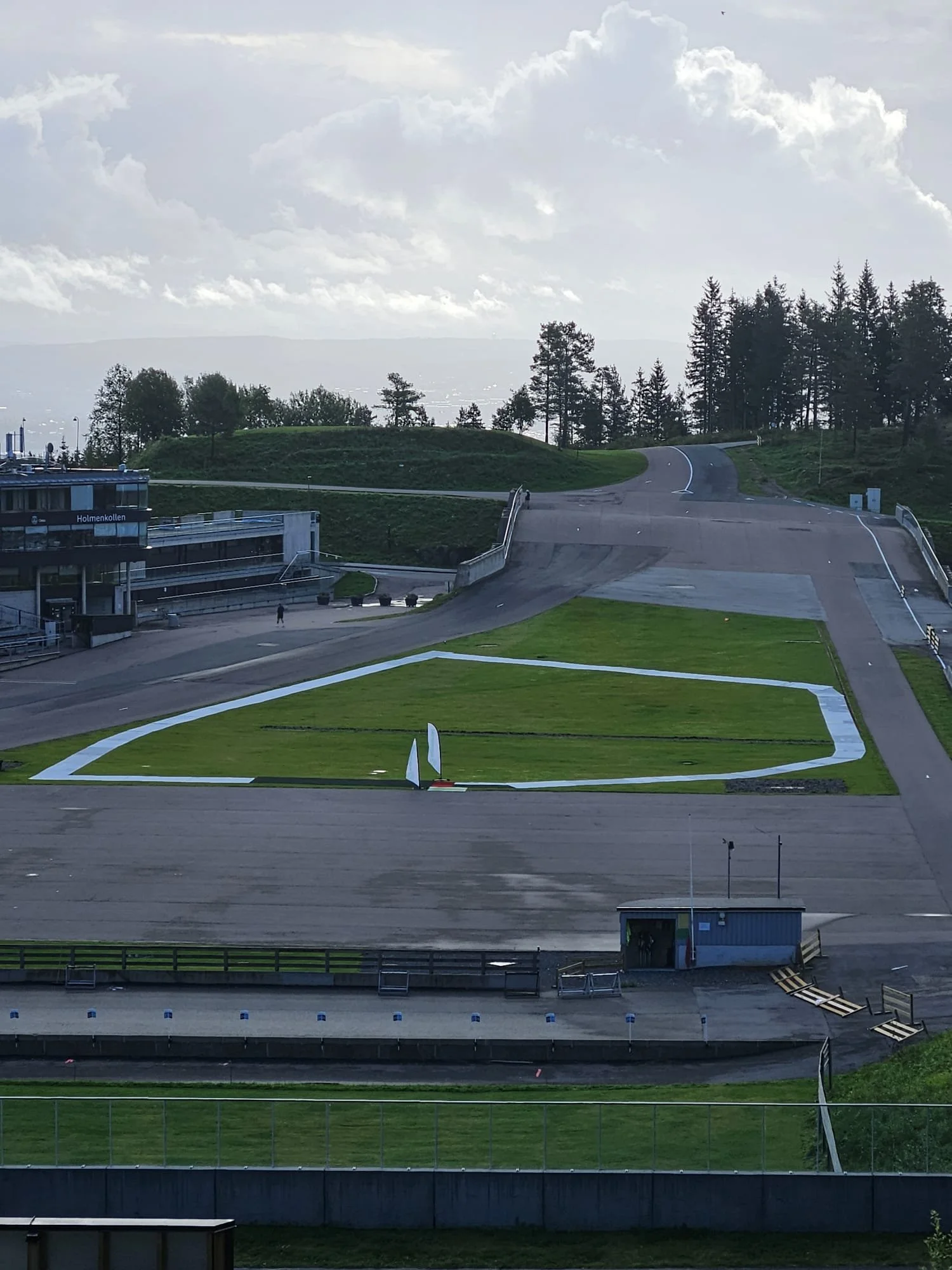 Konstgjord bana för höjdhopp eller längdhopp, nära en idrottsarena, med gröna områden och ett par små tält.