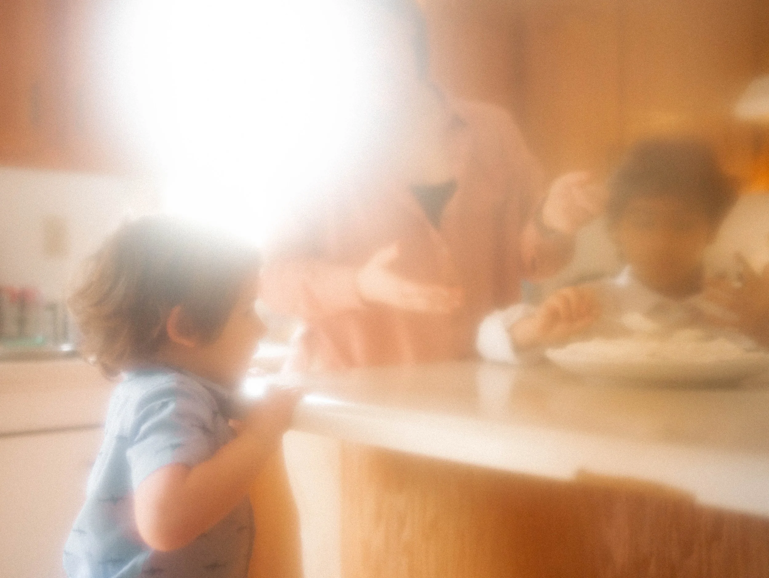 Trois personnes, une mère et ses deux enfants, en train de décorer un gâteau de fête sur un îlot dans une cuisine en bois.