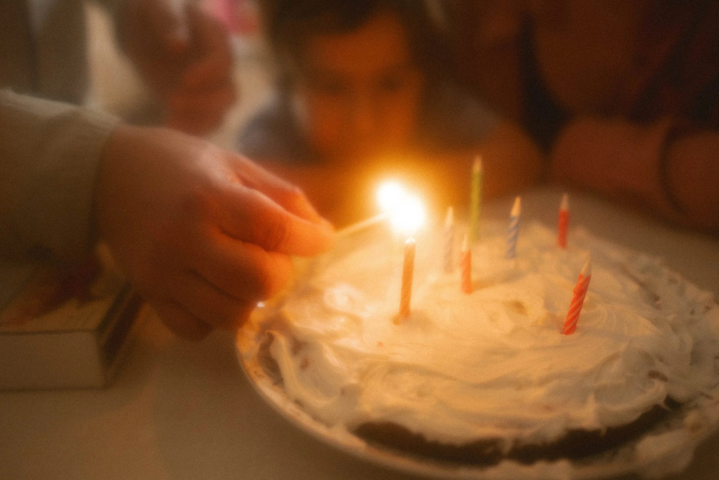 Des mains d'homme qui allume les chandelles sur un gâteau d'anniversaire.