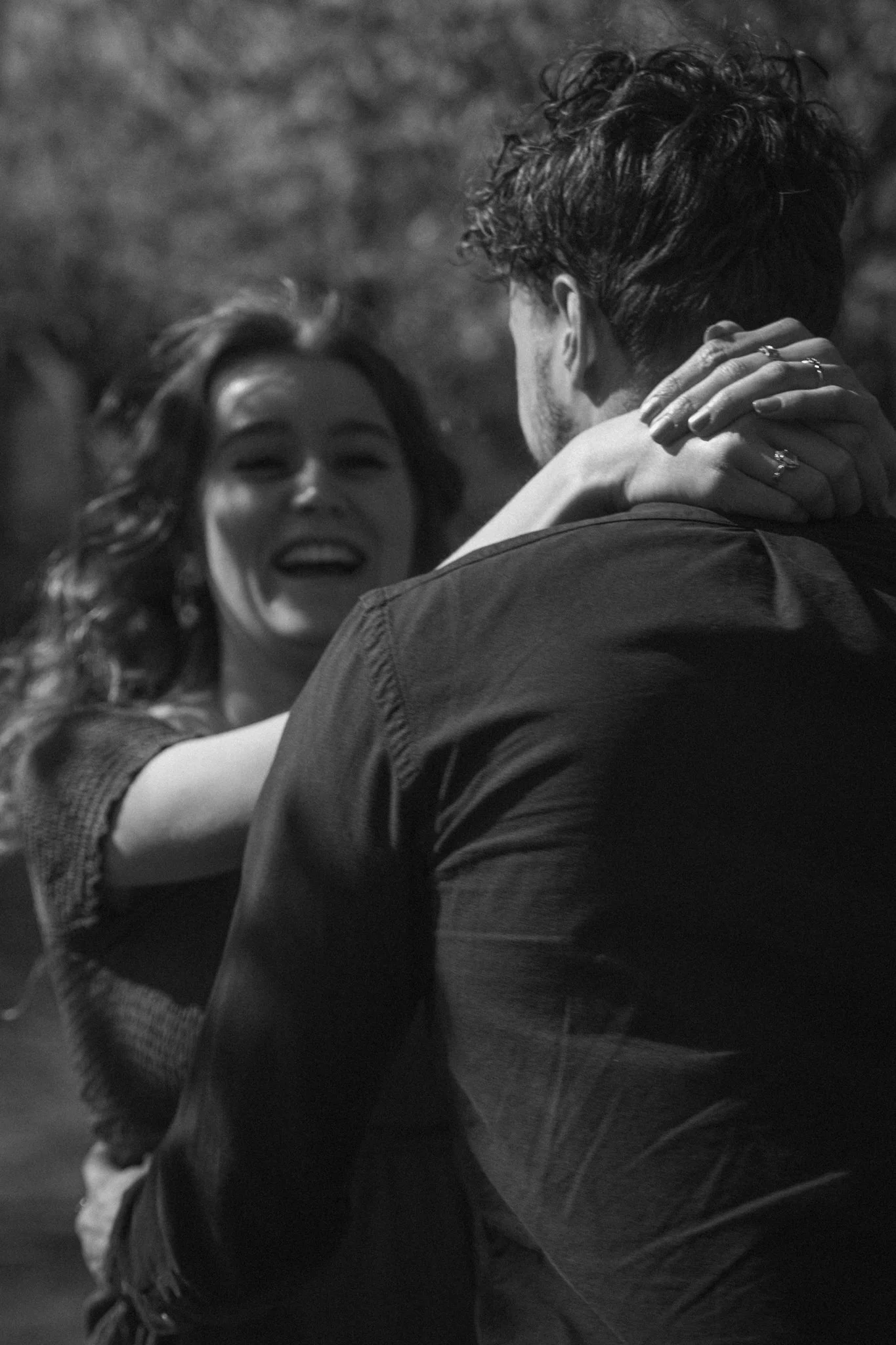 A couple dancing closely outdoors at night, with the woman smiling and the man holding her. Both are casually dressed.