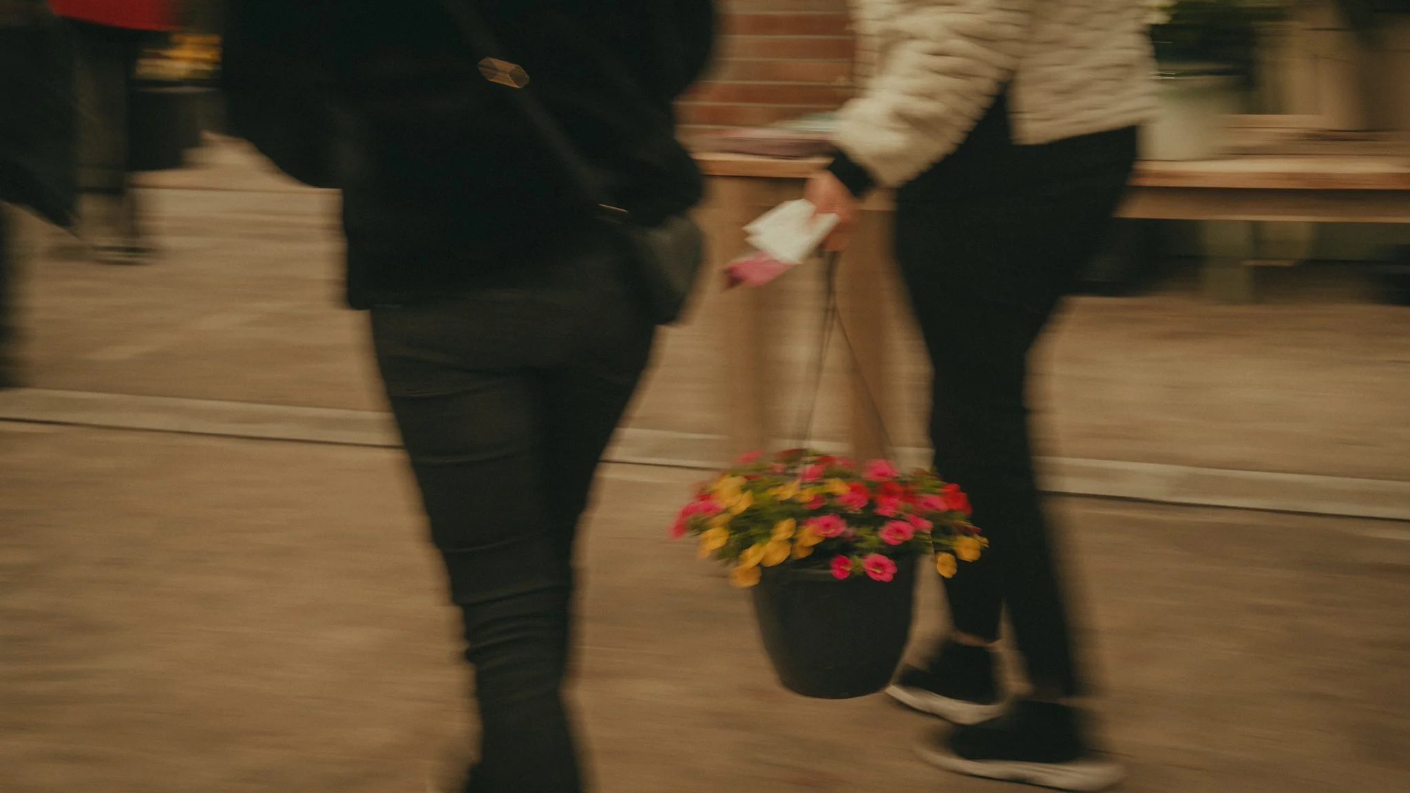 People exchanging flowers in a blurred indoor setting.