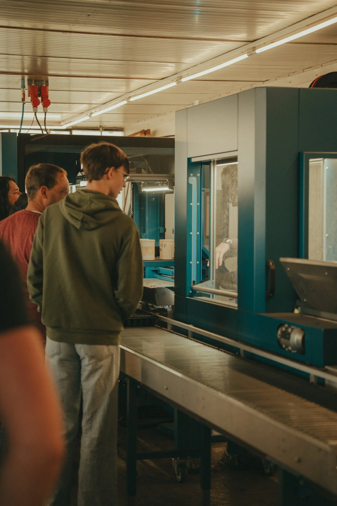 People standing in front of a large machine in a workshop or factory setting.
