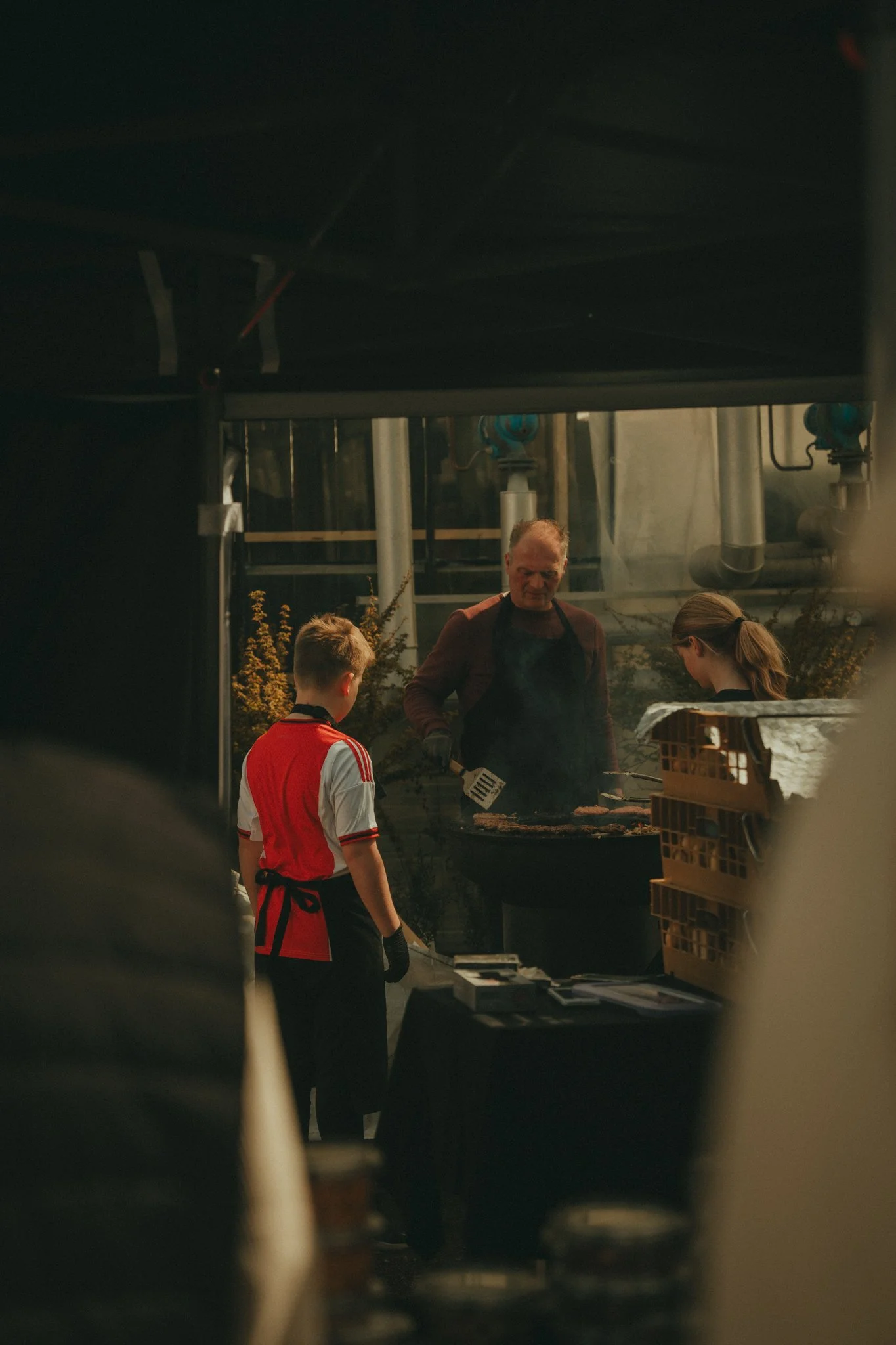 A man and two children preparing food outdoors near a grill.