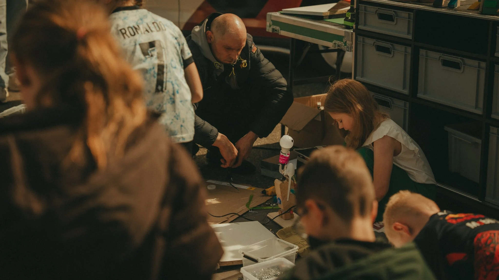 People gathered around a table with a robot arm and various electronic components.