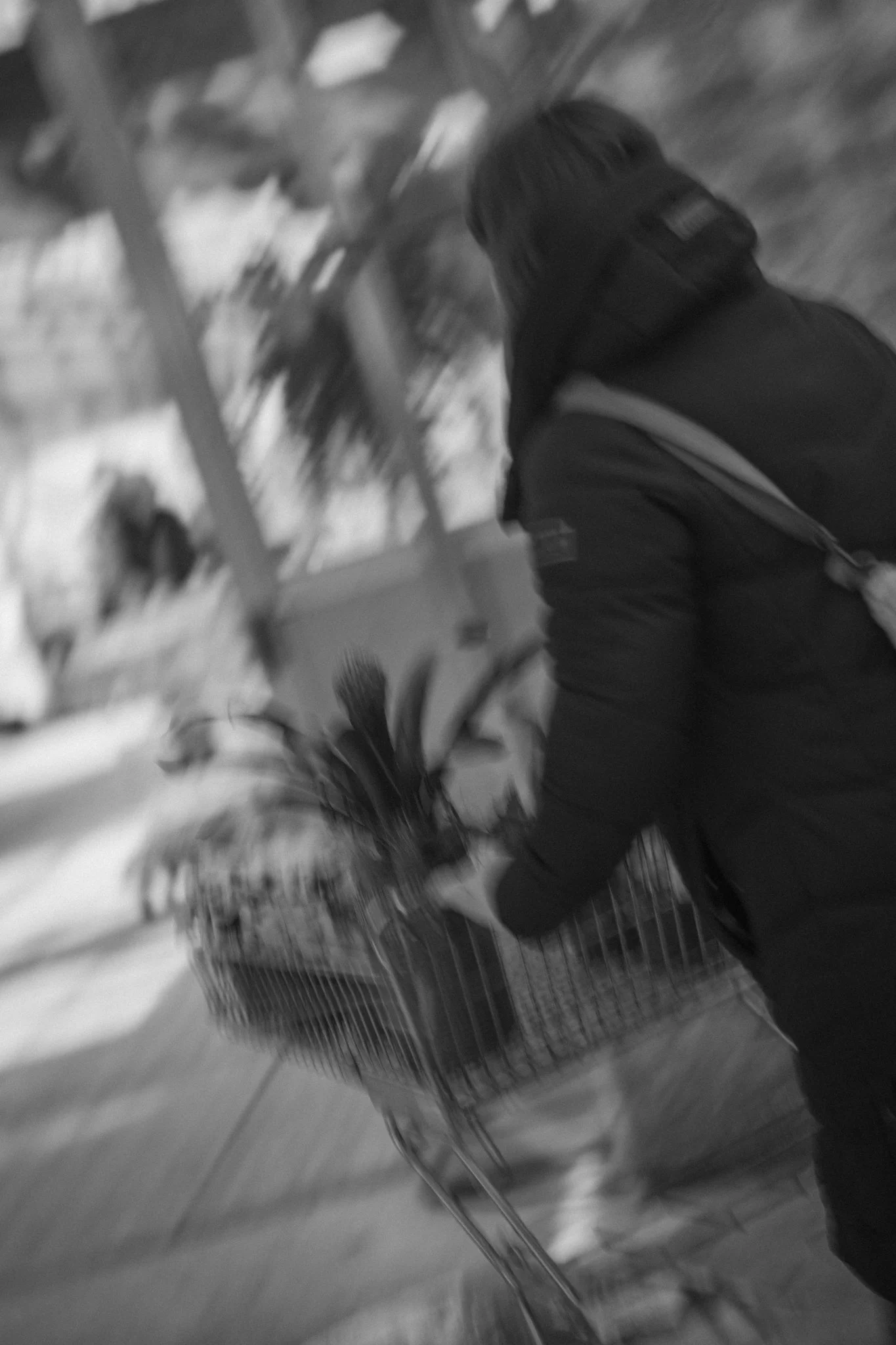 A person walking with a shopping cart in an indoor setting, blurred motion.