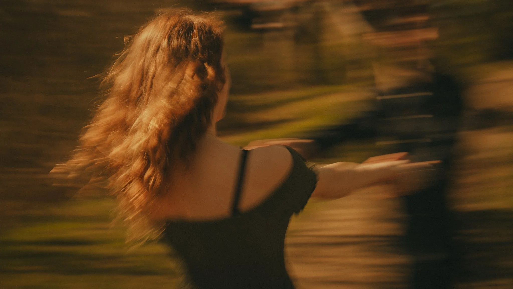 Blurry image of a woman with long hair running outdoors at night, holding a phone in her right hand.