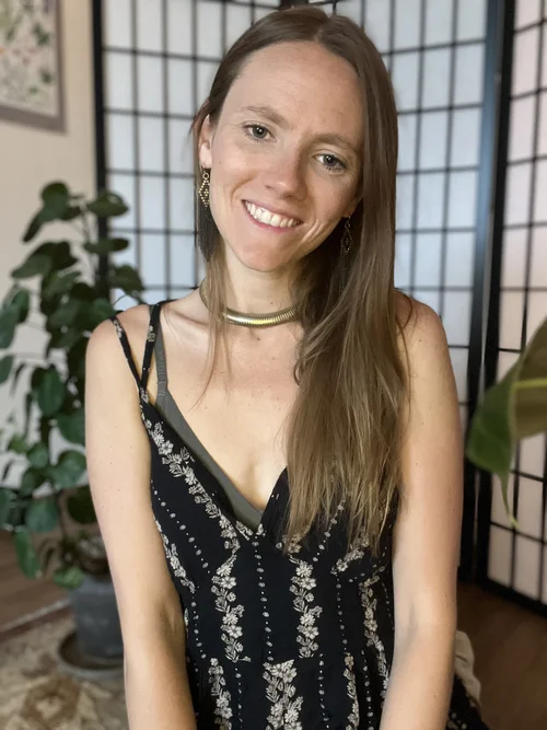 Julia Dyer smiling in front of a folding screen and houseplants