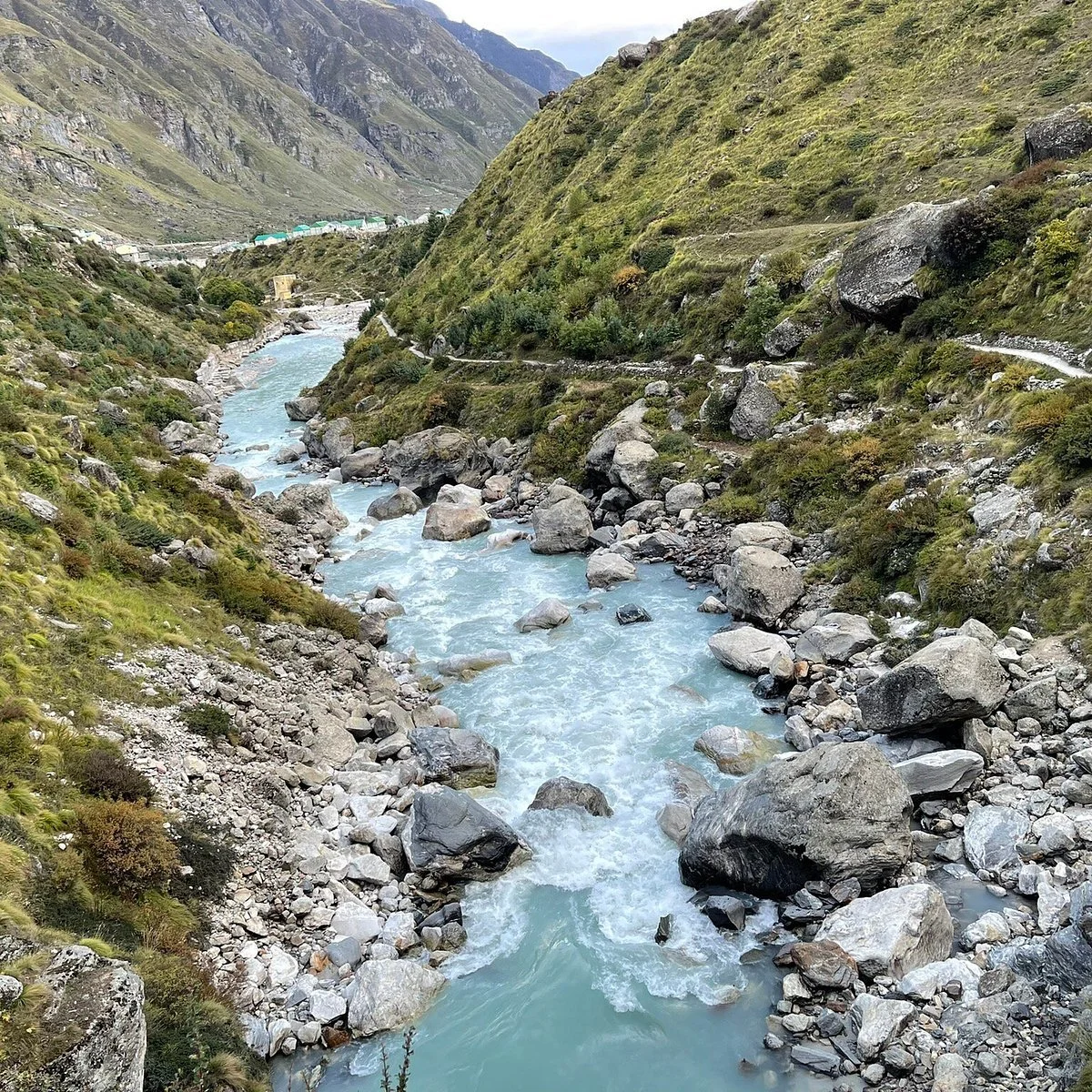 Mountain landscape with a river flowing through a rocky valley and green hillsides.