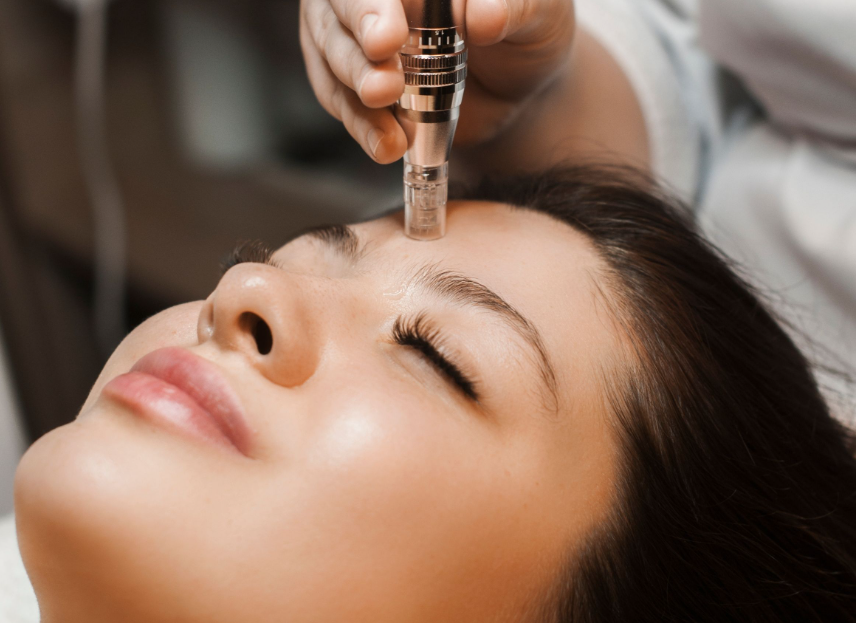 A woman receiving a facial treatment with a handheld device on her forehead at a spa or clinic.