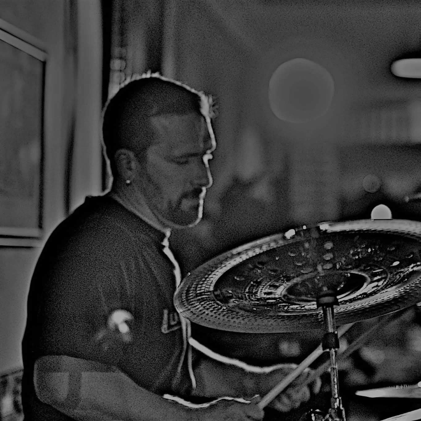 A person playing cymbals, with a dark background and soft lighting