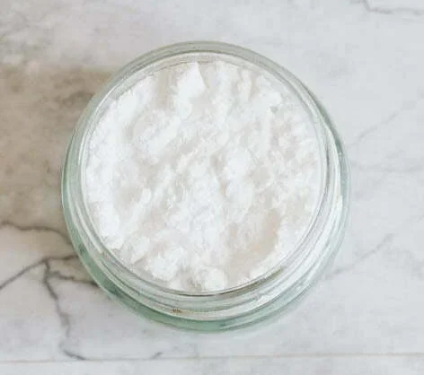 A jar filled with a white powder on a marble surface