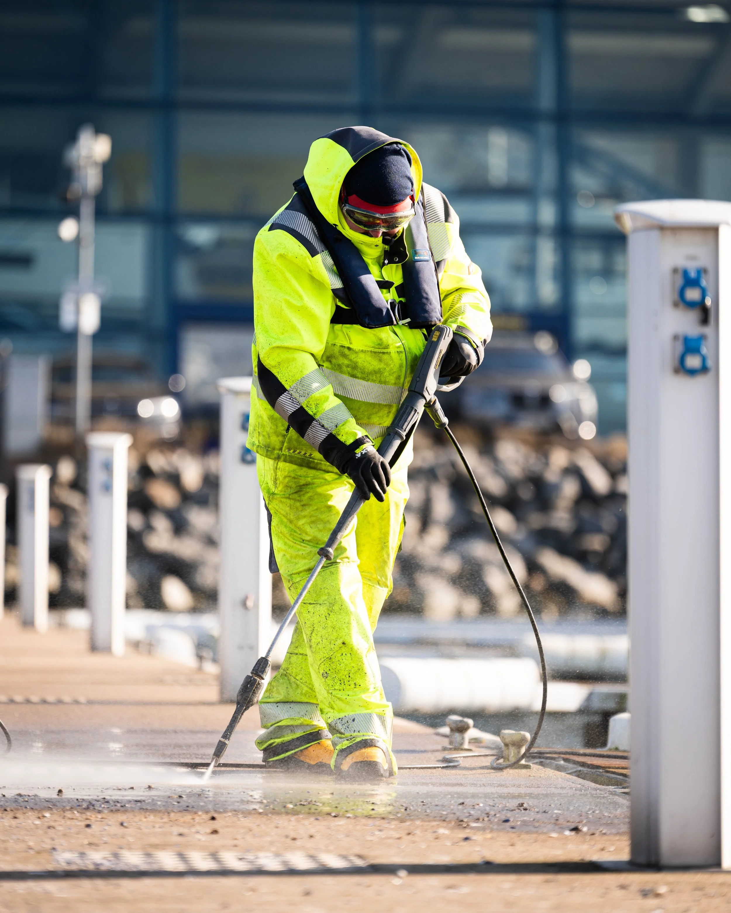 Ein Bauarbeiter in einem neongelben Sicherheitsanzug benutzt eine Bohrmaschine auf einer Baustelle.