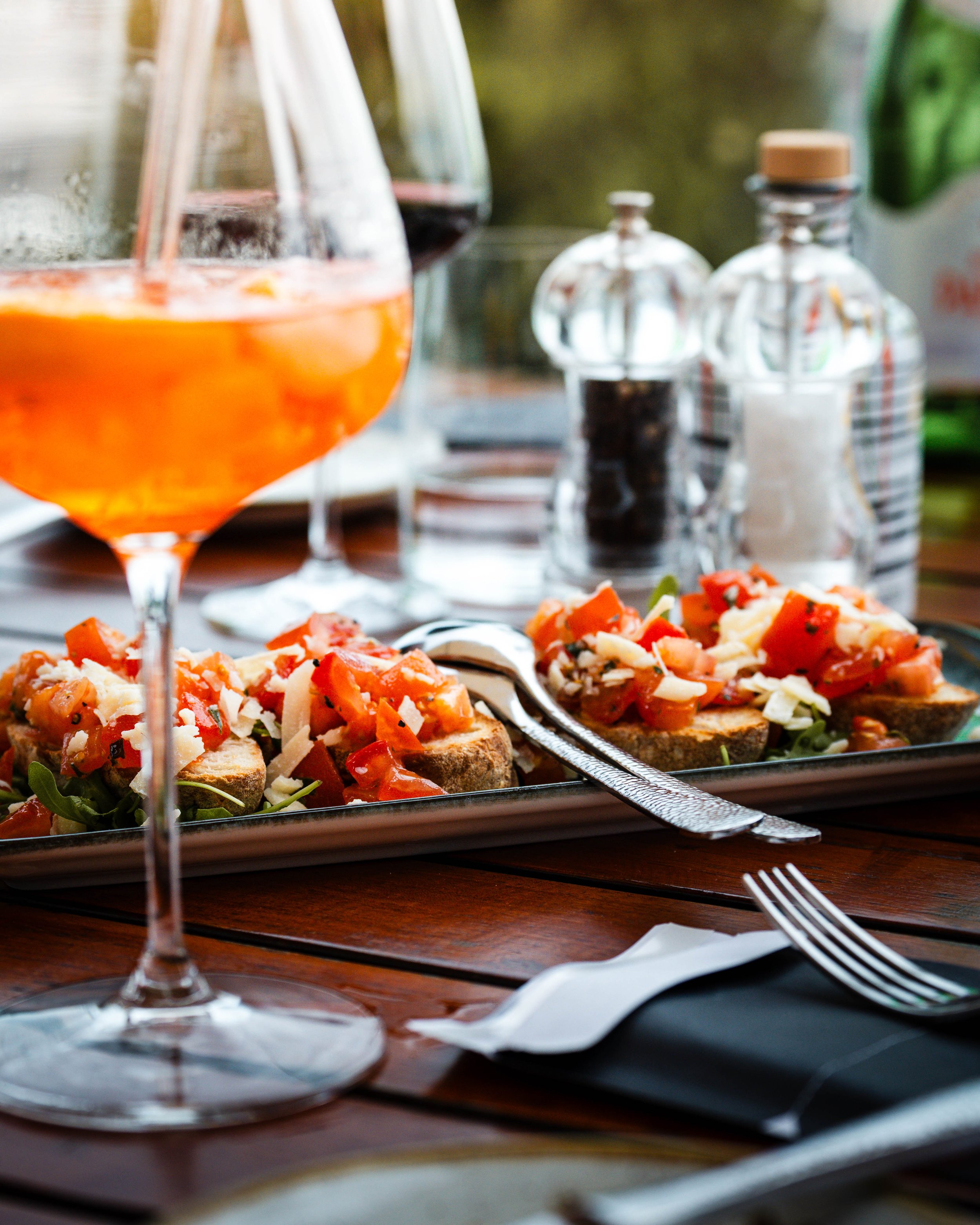 Brotzeit mit geröstetem Brot, Tomaten und Käse, two glasses of rosé wine, Salz- und Pfeffermühlen auf dem Tisch.