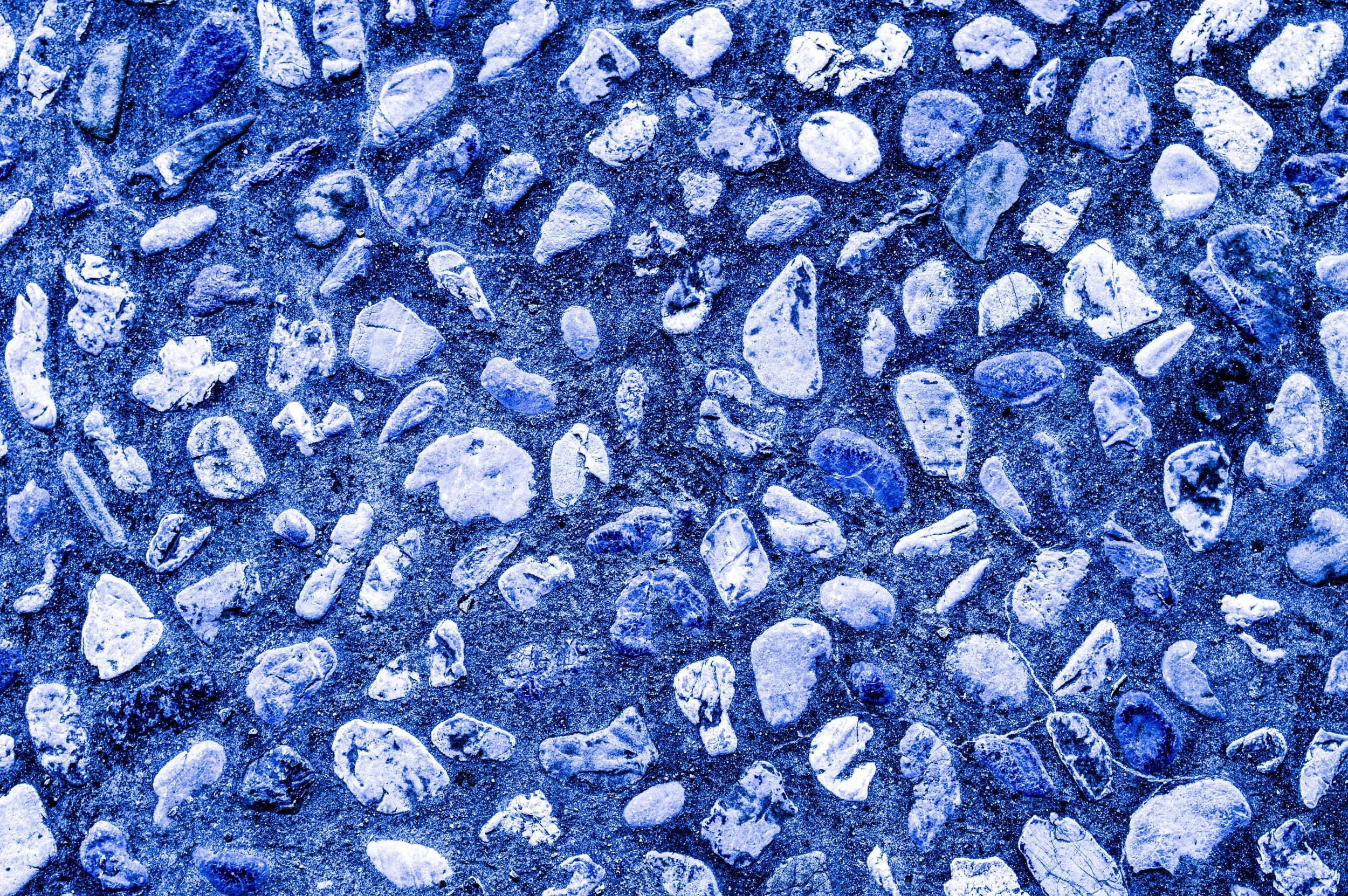 Close-up of small rocks and gravel on a surface, with a blue tint.