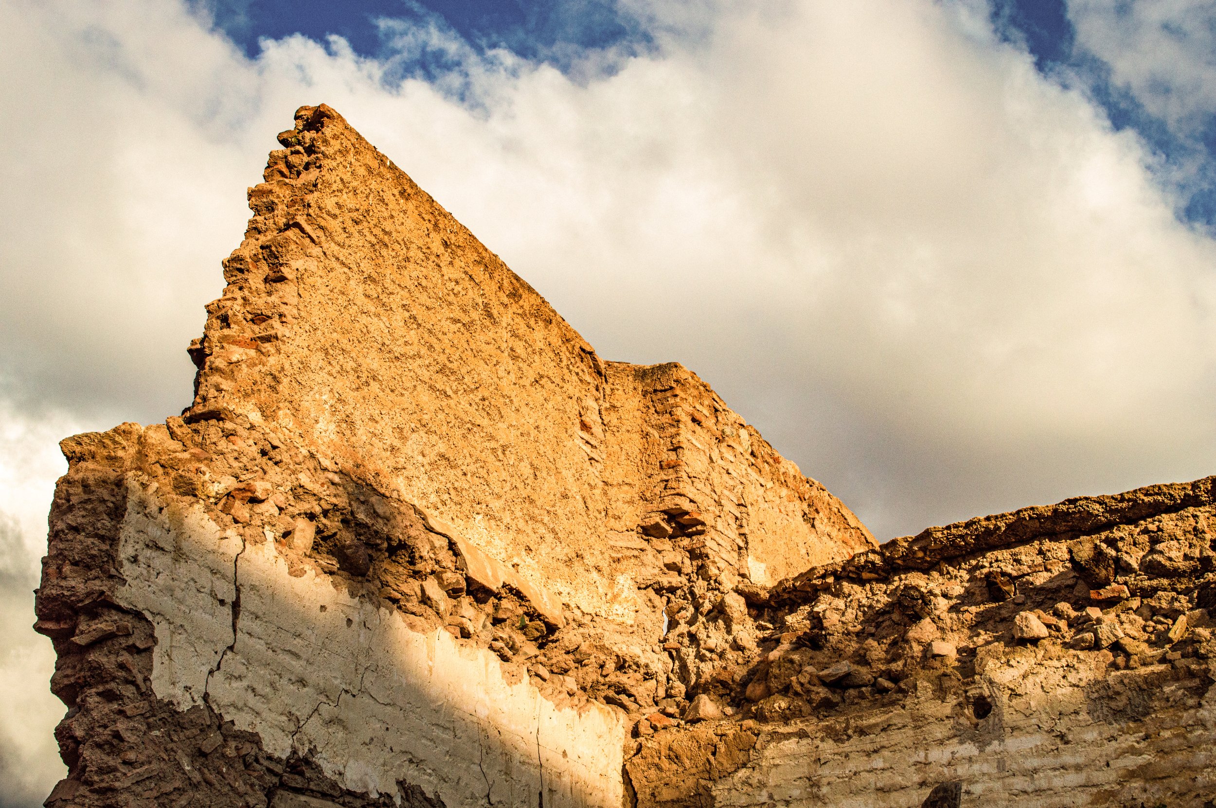 Close-up of an ancient stone wall with uneven, weathered bricks against a partly cloudy sky.
