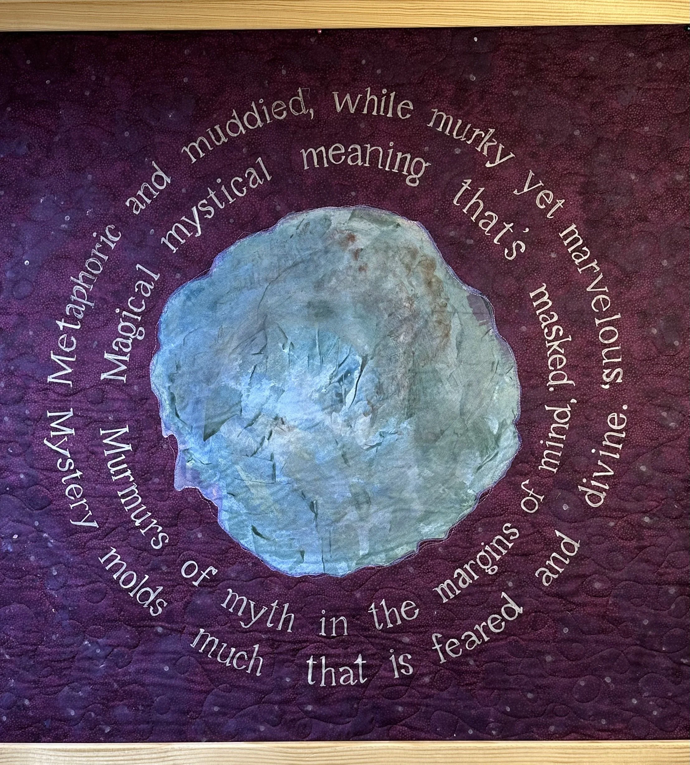 Close-up of a circular quote written in white text on a purple background with tiny white dots, framed by a light wooden border.