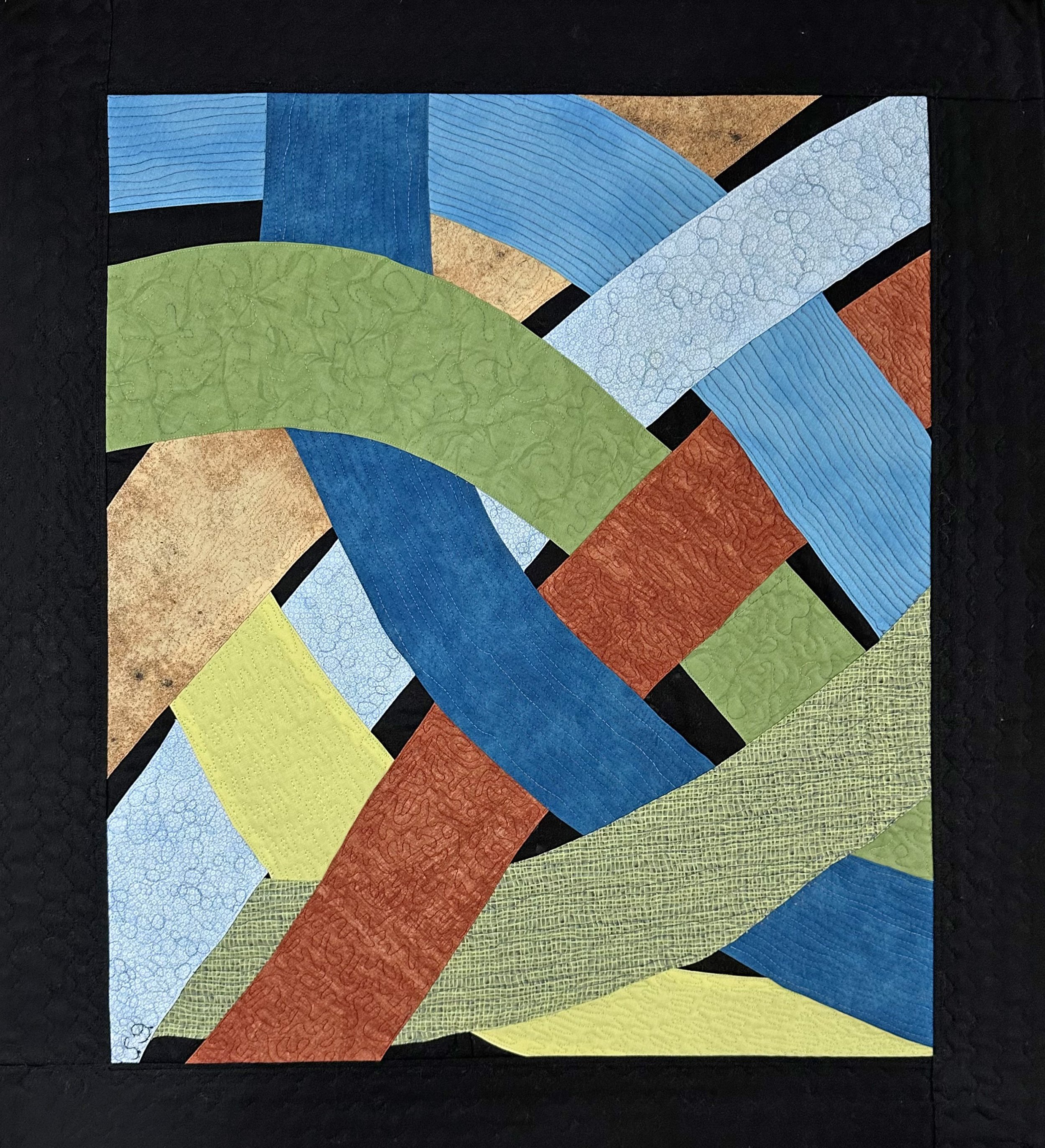 Colorful quilt featuring various stitched fabric patterns, arranged in curved strips with a black border.