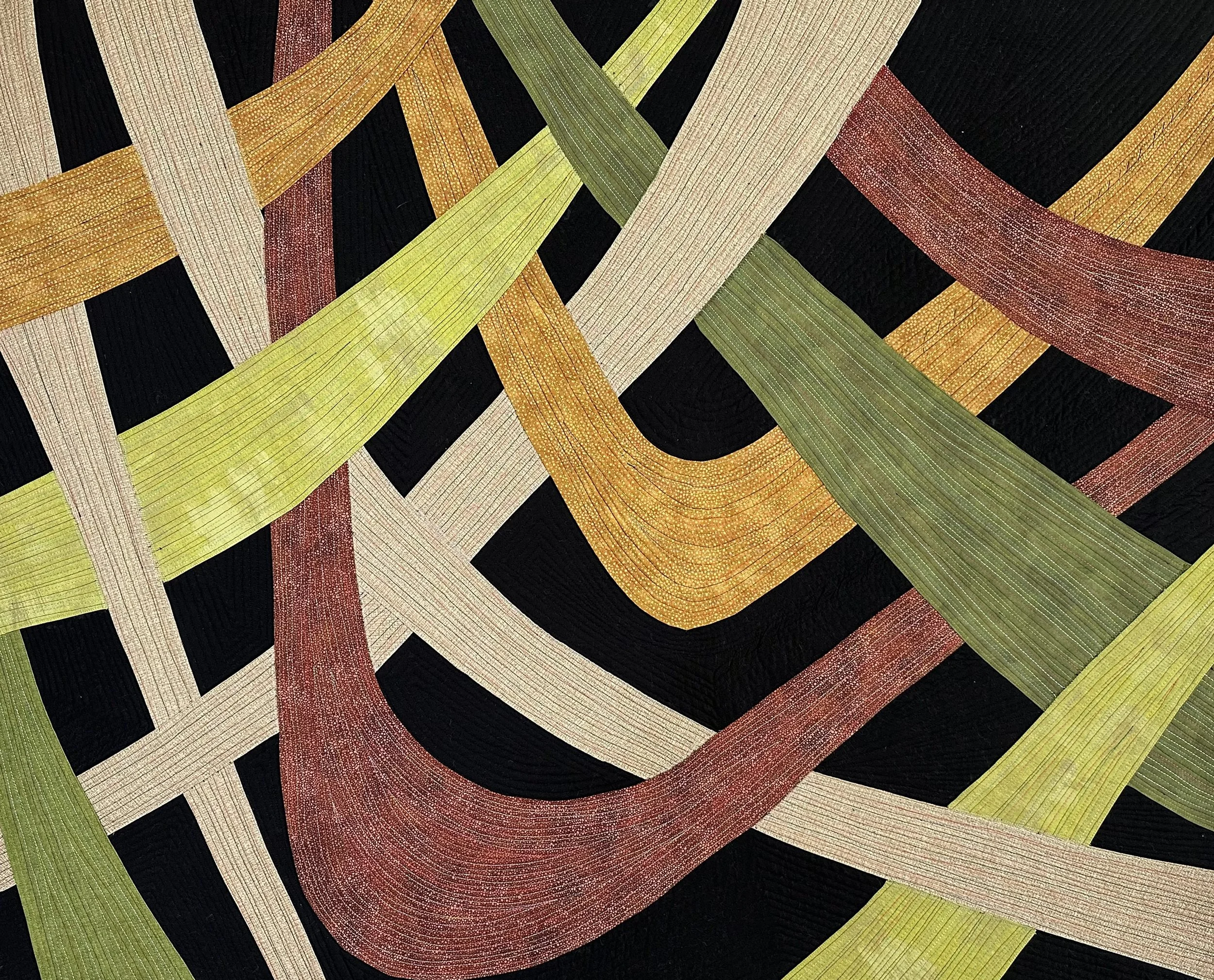 Close-up of a colorful woven textile with intersecting strips of yellow, red, beige, green, and black, creating a geometric pattern.