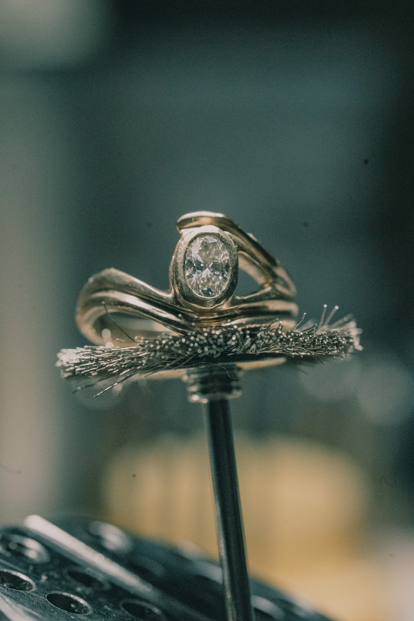 Close-up of a diamond ring with a band that has a swirl design, secured in a piece of jewelry foam.
