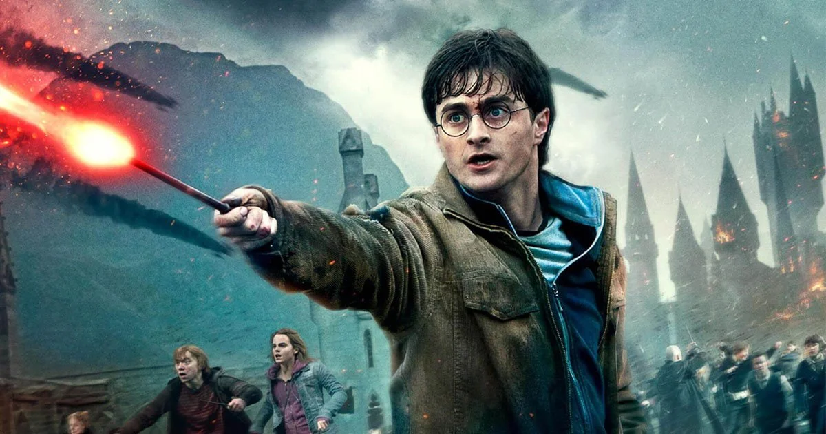 Harry Potter, wearing glasses and a jacket, raising a wand emitting a red light in a scene of chaos and destruction, with a dark, stormy sky and flying debris. Other people are seen running in the background amidst a burning castle or fortress.