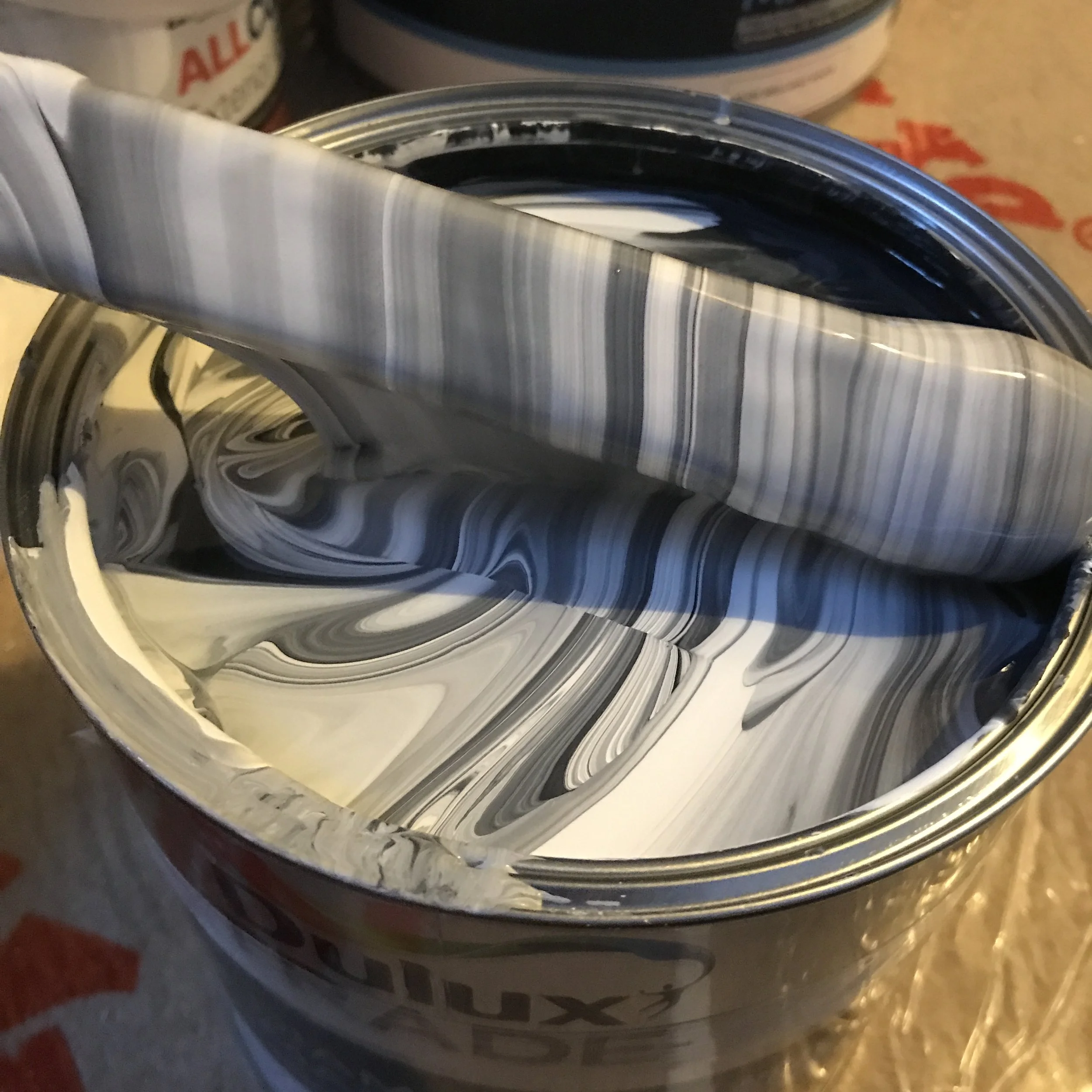 Close-up of an open can of black and white marbled paint with a spatula resting on top.