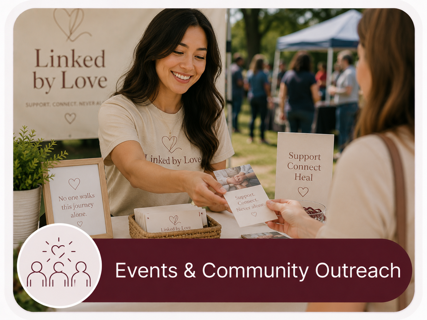 A woman at a community outreach booth labeled "Linked by Love" is handing a flyer to another woman. The booth promotes support, connection, and healing, with signs that say "No one walks this journey alone" and "Support. Connect. Heal." There are more people and tents in the background at an outdoor event.