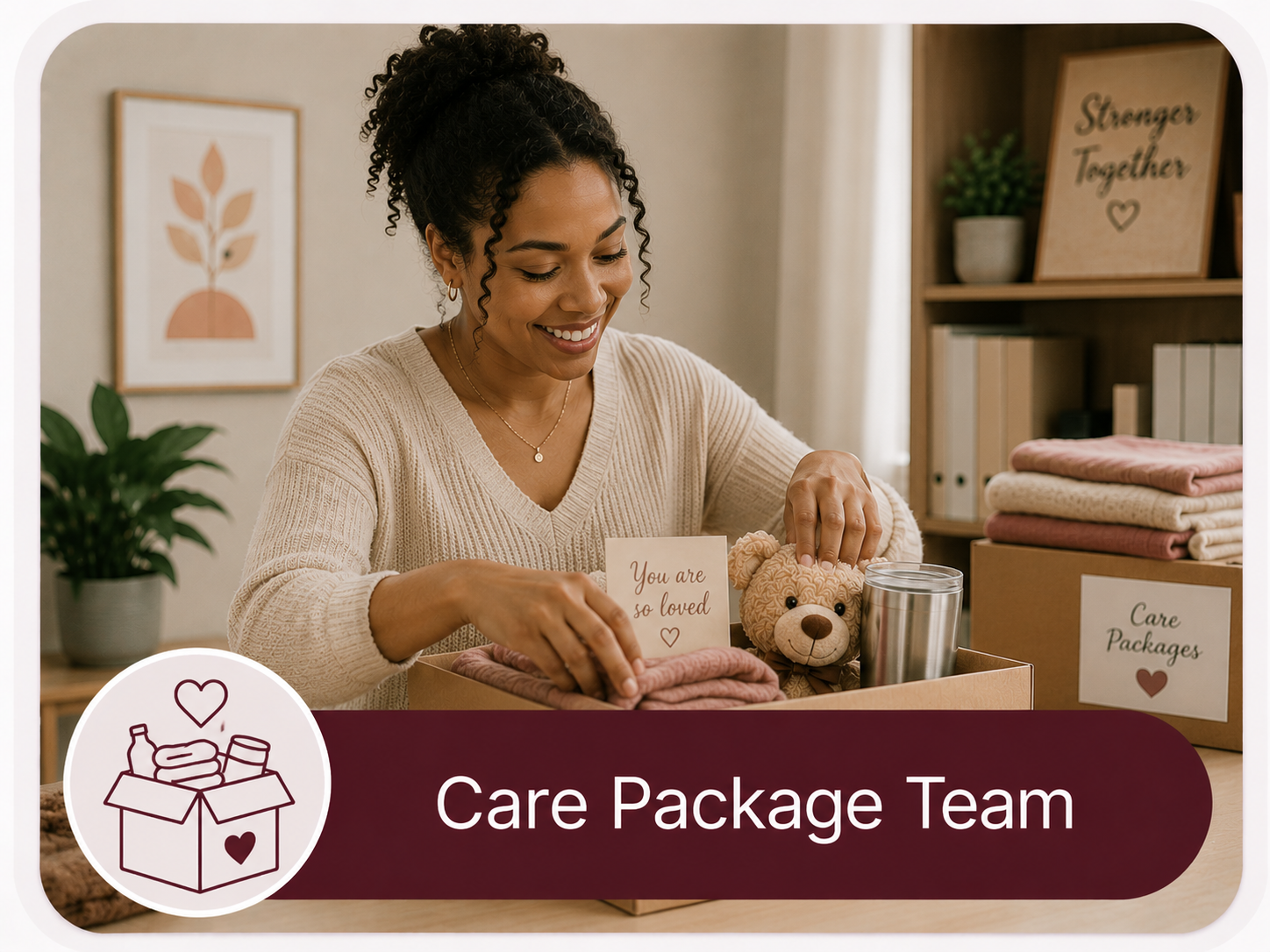 A smiling woman packing a care package with stuffed teddy bear, a stainless steel tumbler, and folded pink and beige blankets. There are signs that say "You are so loved" and "Care Packages" in the background. The scene features plants and framed artwork.