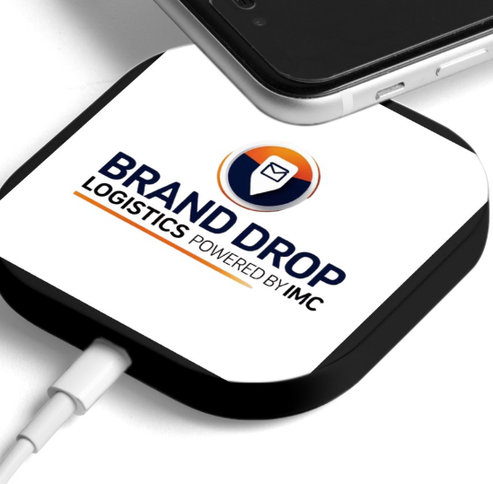 Close-up of smartphone screen displaying the logo of 'BRAND DROP LOGISTICS powered by IMC'. The phone is connected with a white charging cable.