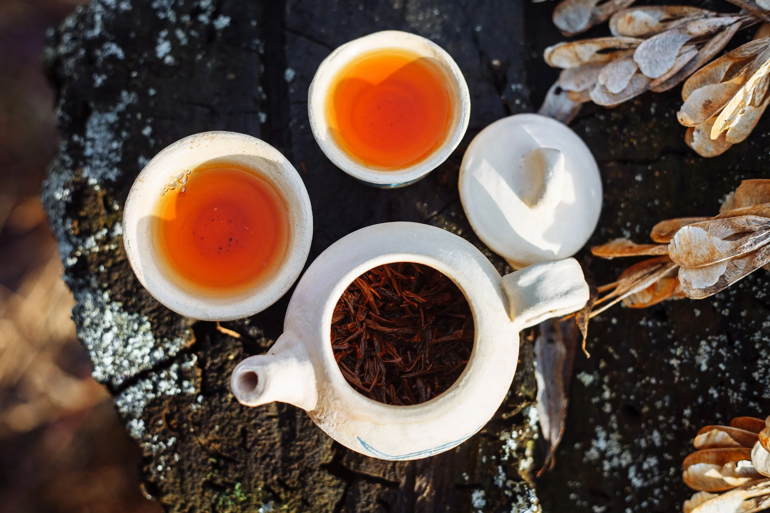 Two tea cups filled with team set alongside a teapot.