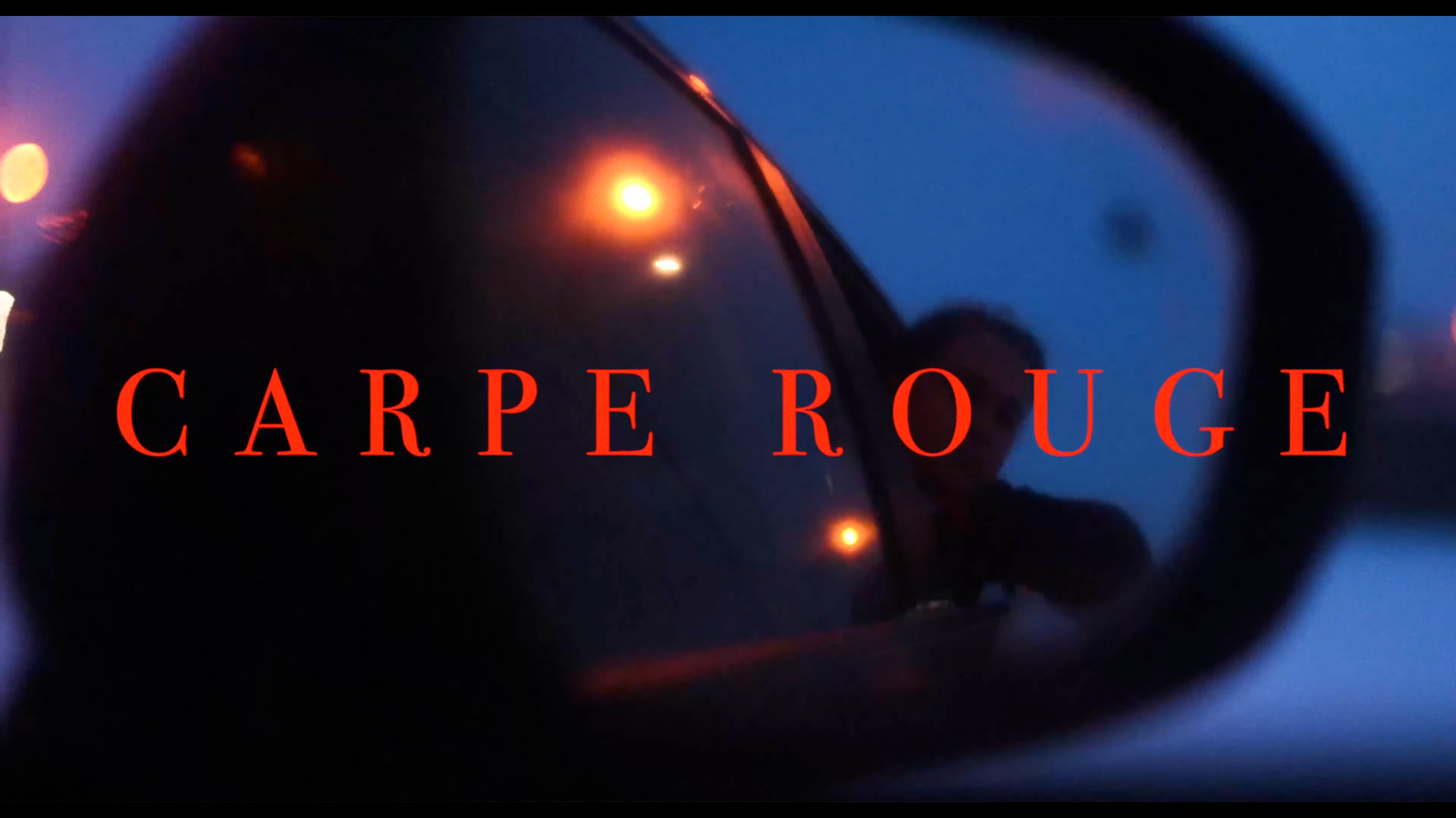 Un reflet dans une lunette de soleil avec le texte 'CARPE ROUGE' en rouge vif, des lumières orange dans un fond bleu foncé.