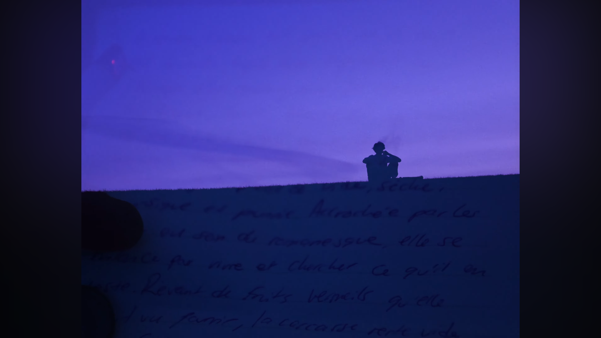 Silhouette d'une personne assise sur une colline au coucher du soleil avec un ciel violet et un texte manuscrit en dessous.