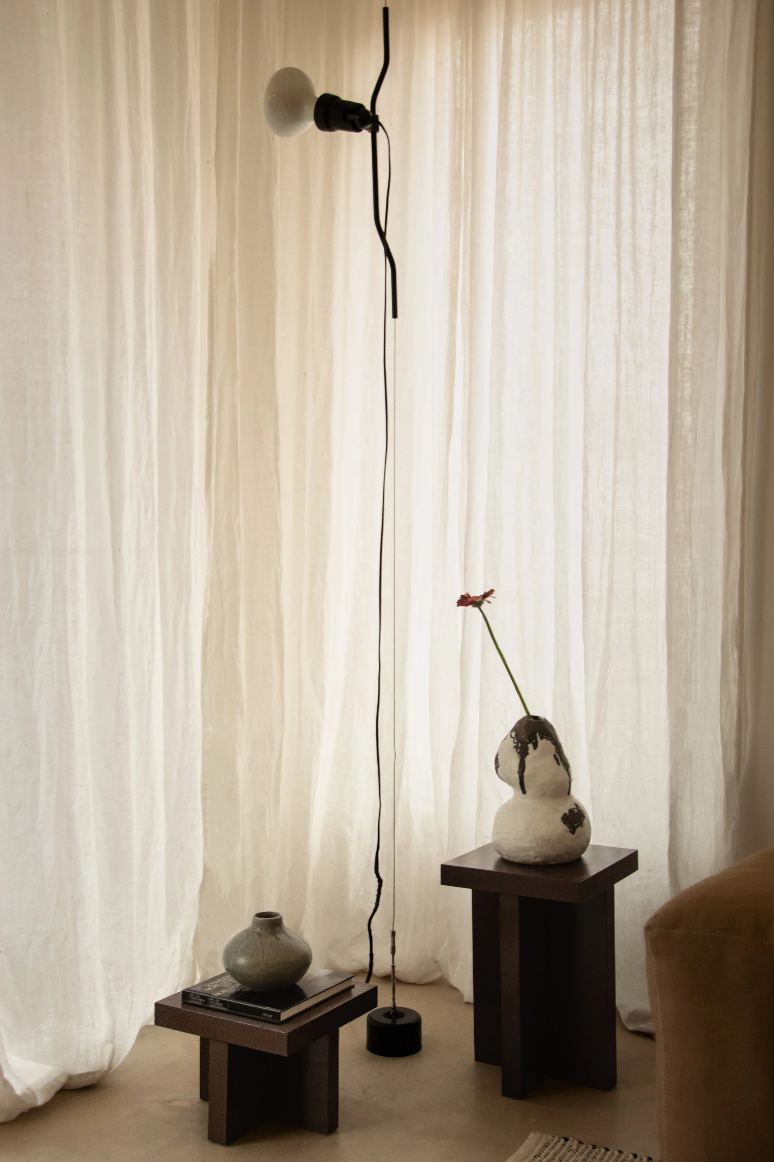 Sculptural floor lamp and ceramic objects within warm contemporary living room