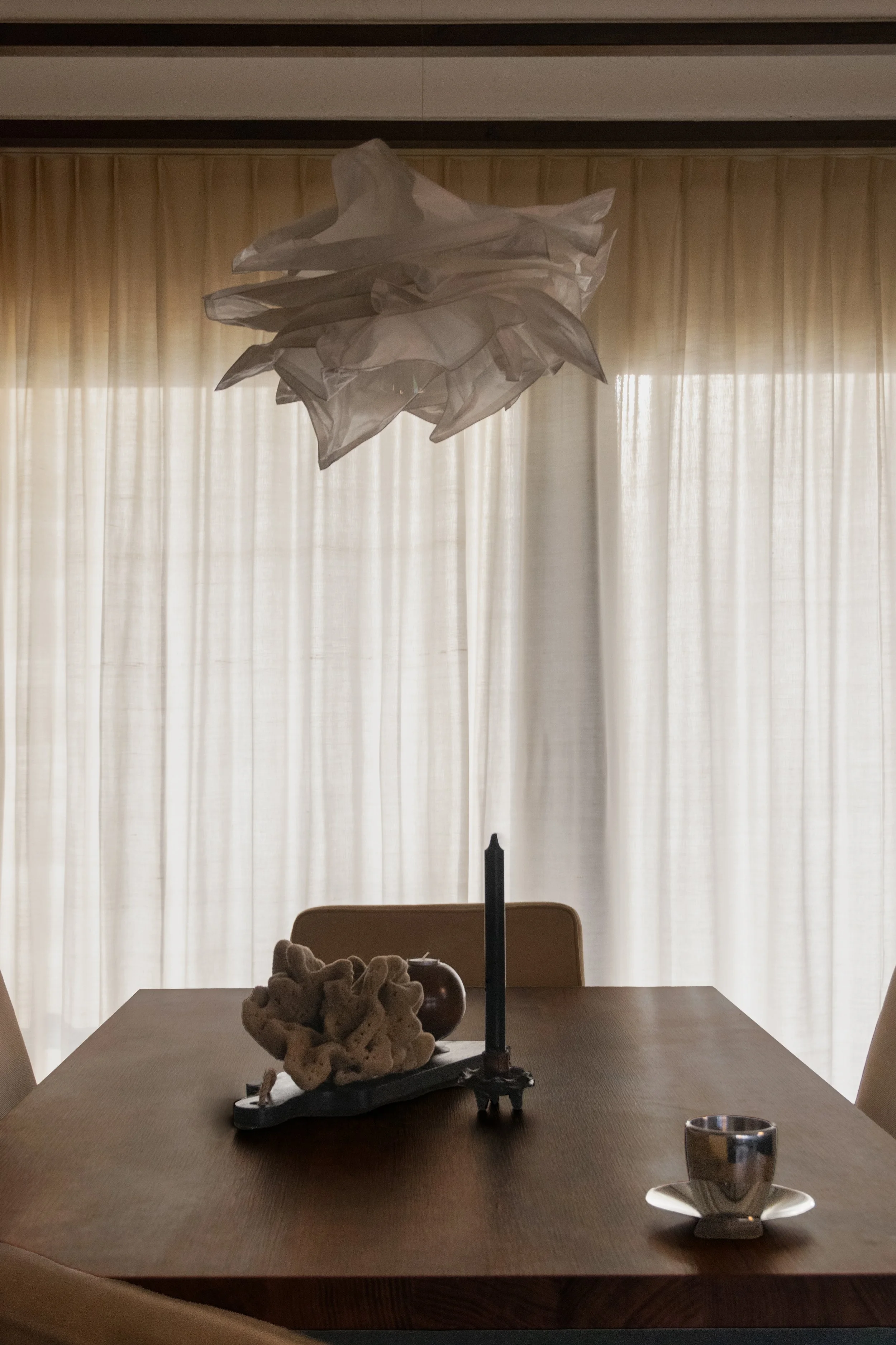 Dining table styling with sculptural pendant light and full-height linen curtains