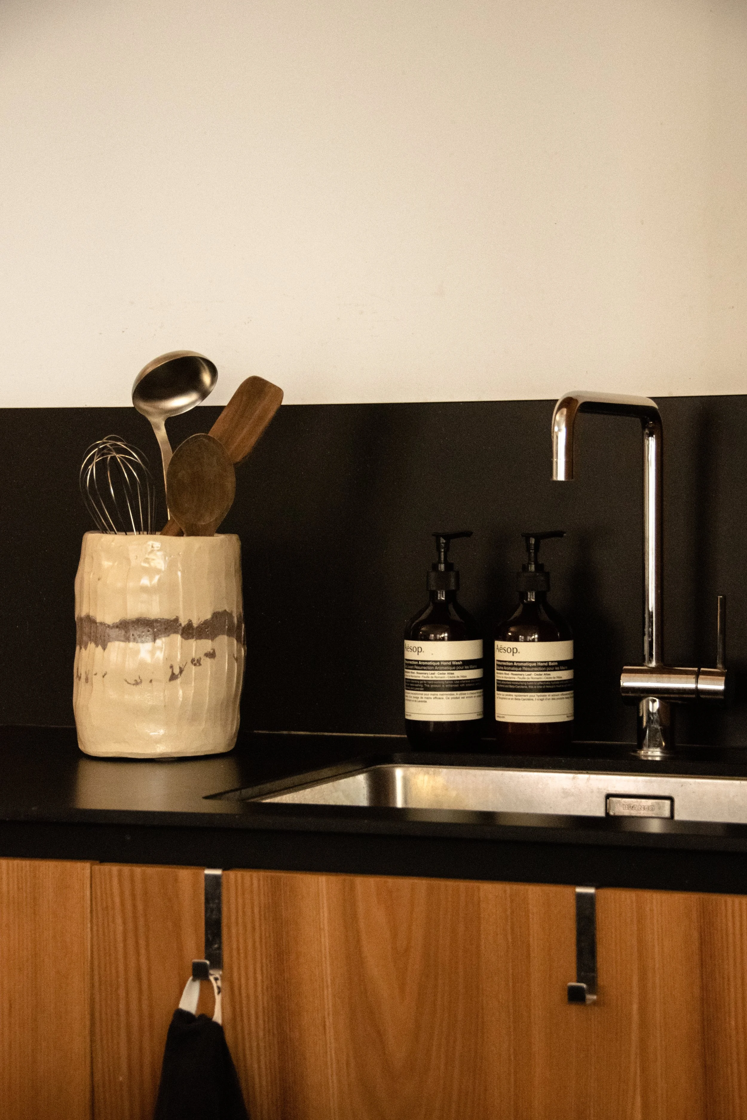 Kitchen styling detail with ceramic utensil holder, black countertop and chrome fixtures