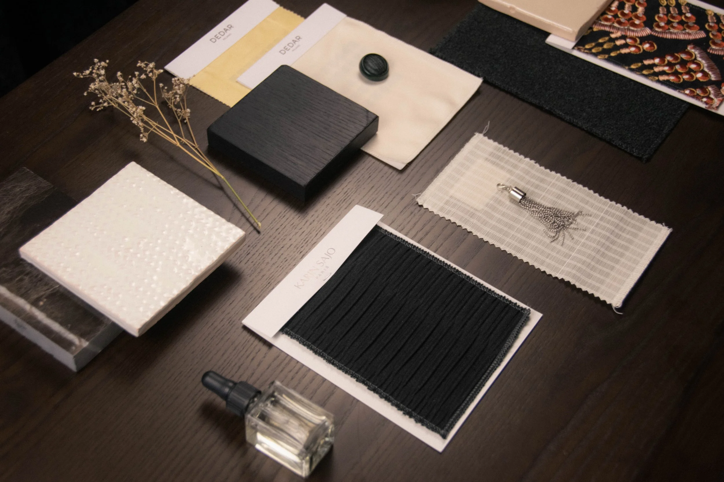 Interior material selection for a Studio Cér project, including DEDAR fabric swatches, a ceramic tile sample and dried flowers.