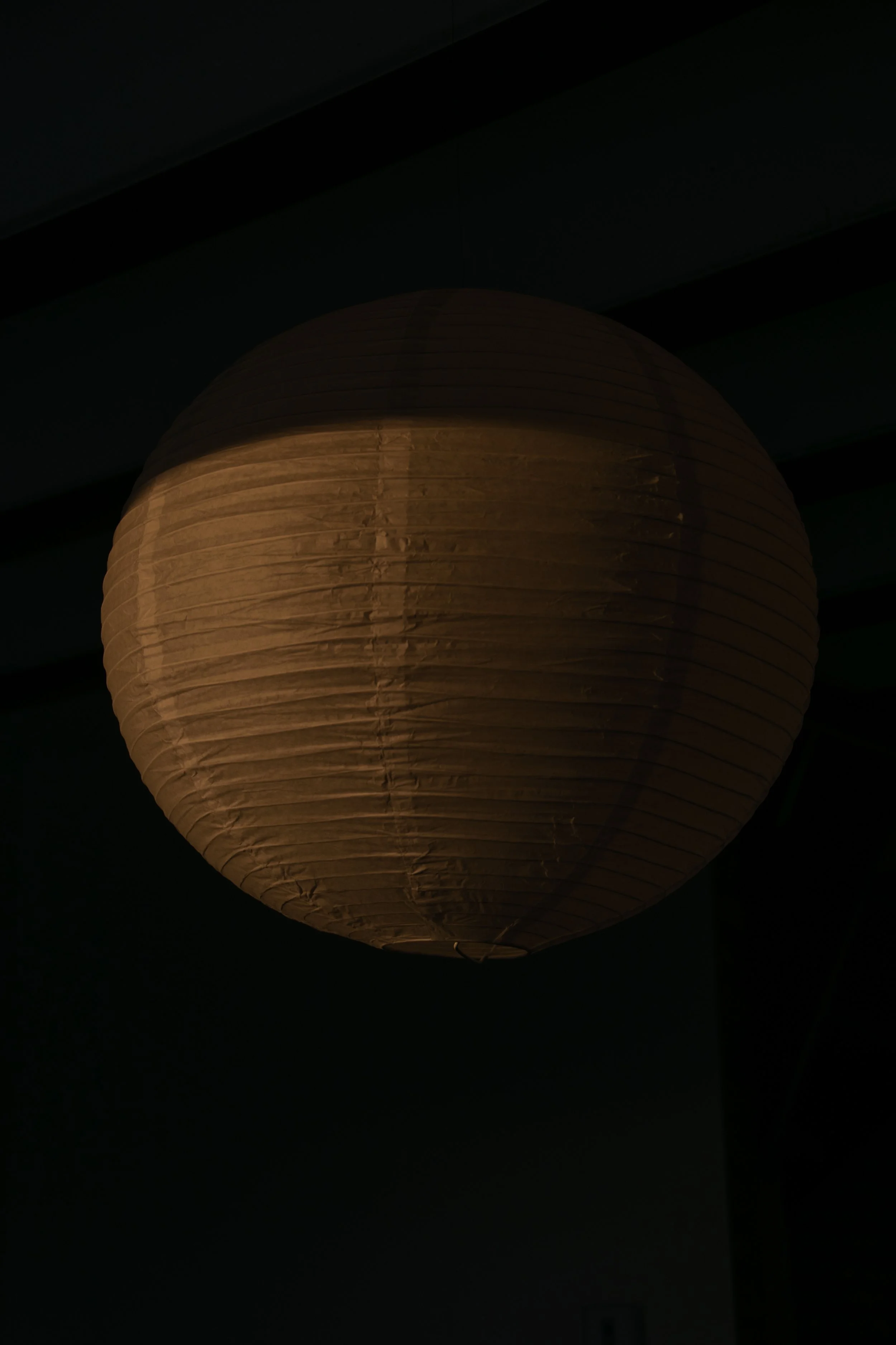 A glowing paper lantern hanging in a dark room.