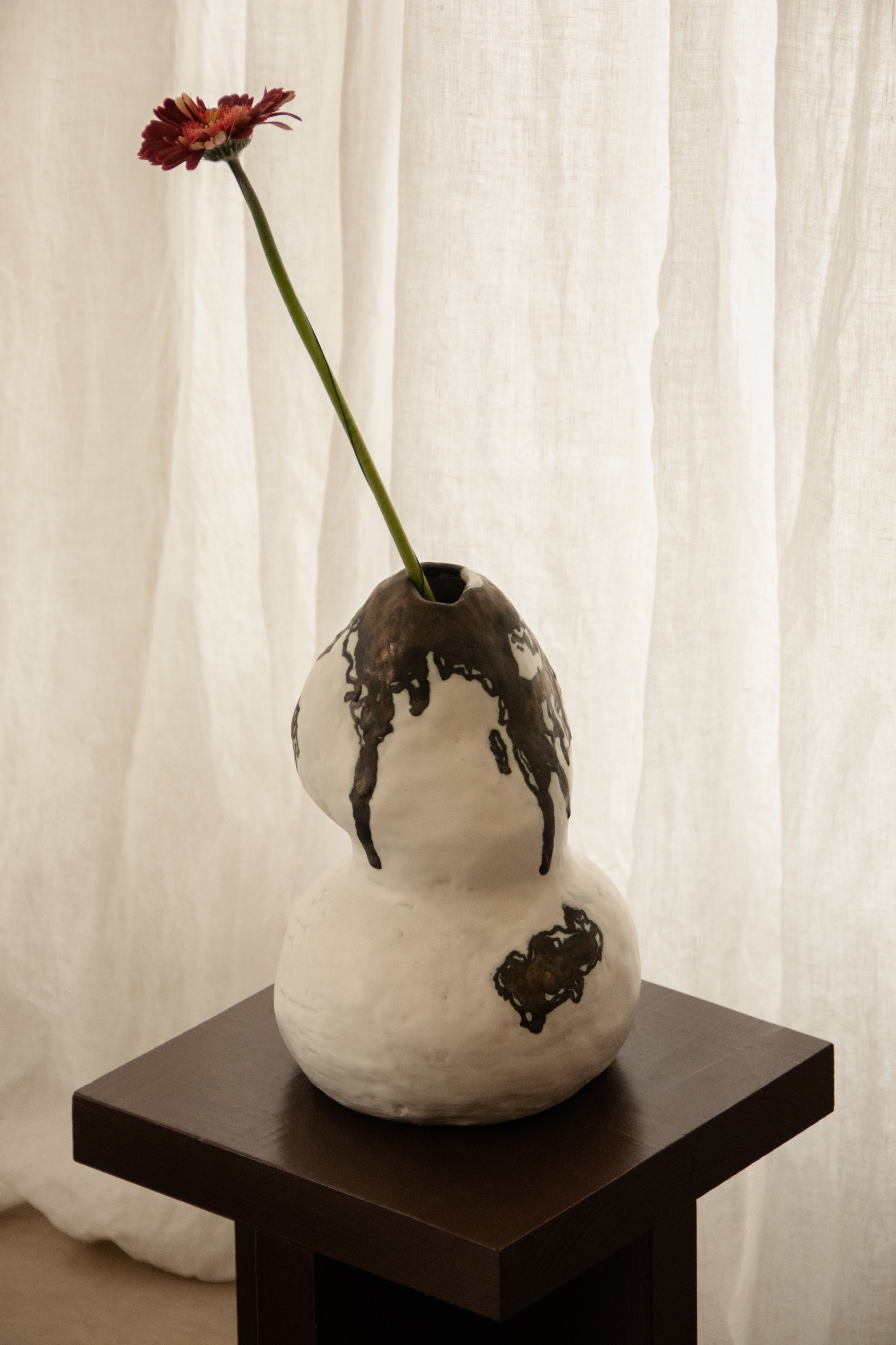 Handmade ceramic vase with floral detail styled against soft linen curtains