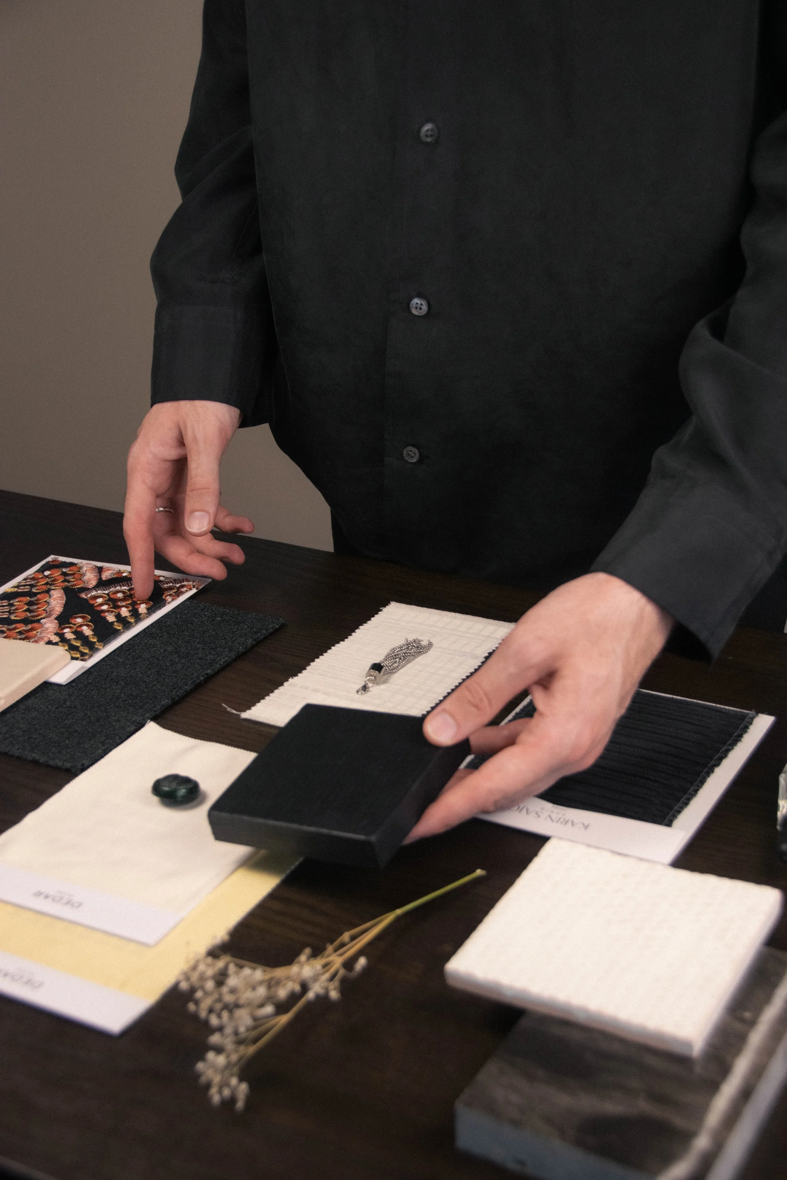 Hands arranging fabric and material samples during a Studio Cér interior design material selection.